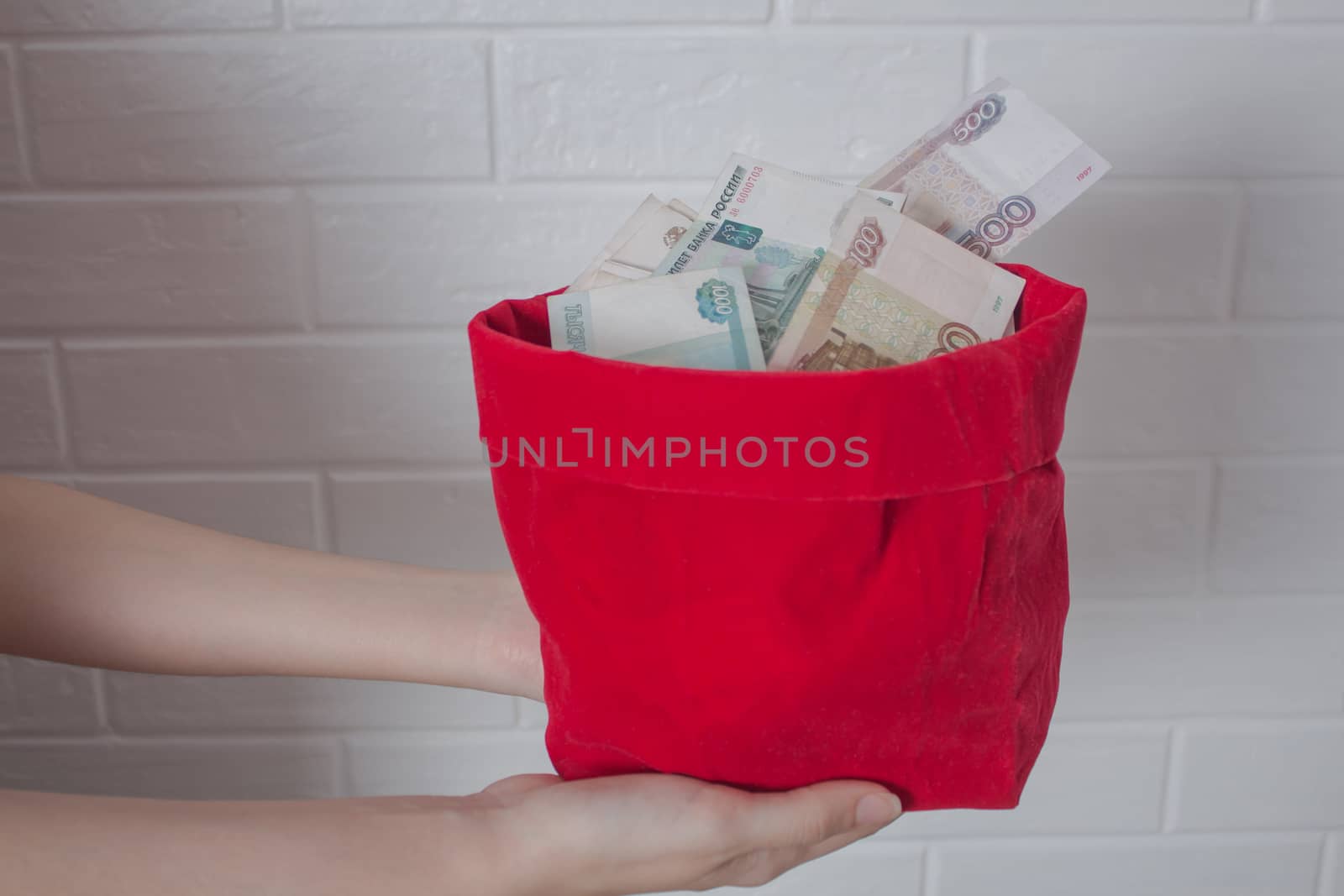 Hands hold a red bag with a lot of Rubles in it. Russian. National currency, banknote. Much money. Business, Economics, and investments. Wealth, accumulation, income.