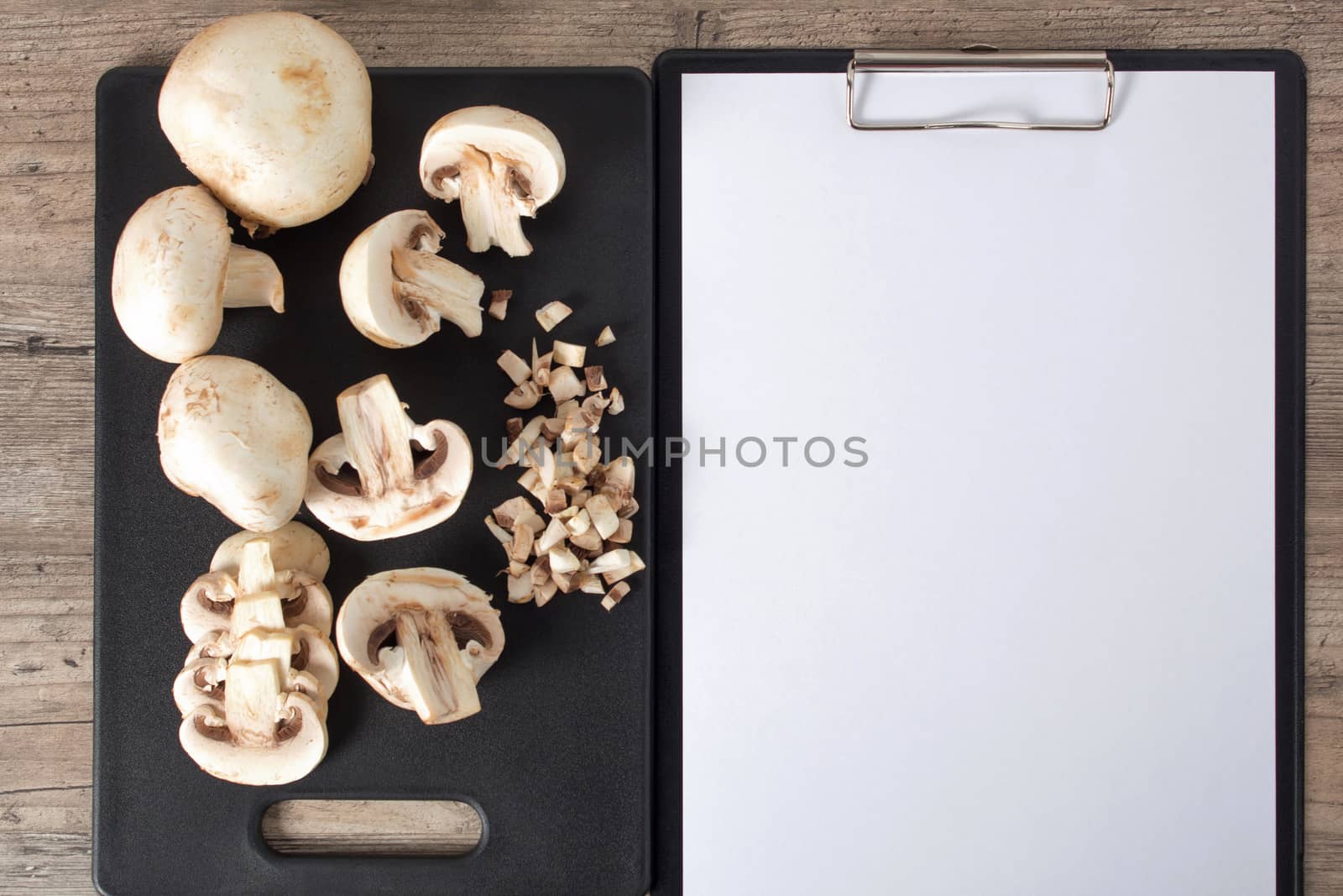 Food. Top view mushrooms on a black cutting board. To cook the champignon. Write down the recipe. Copy space, clear space. Tablet with a blank sheet of paper. Vegan, vegetarian, dietary, diabetic.
