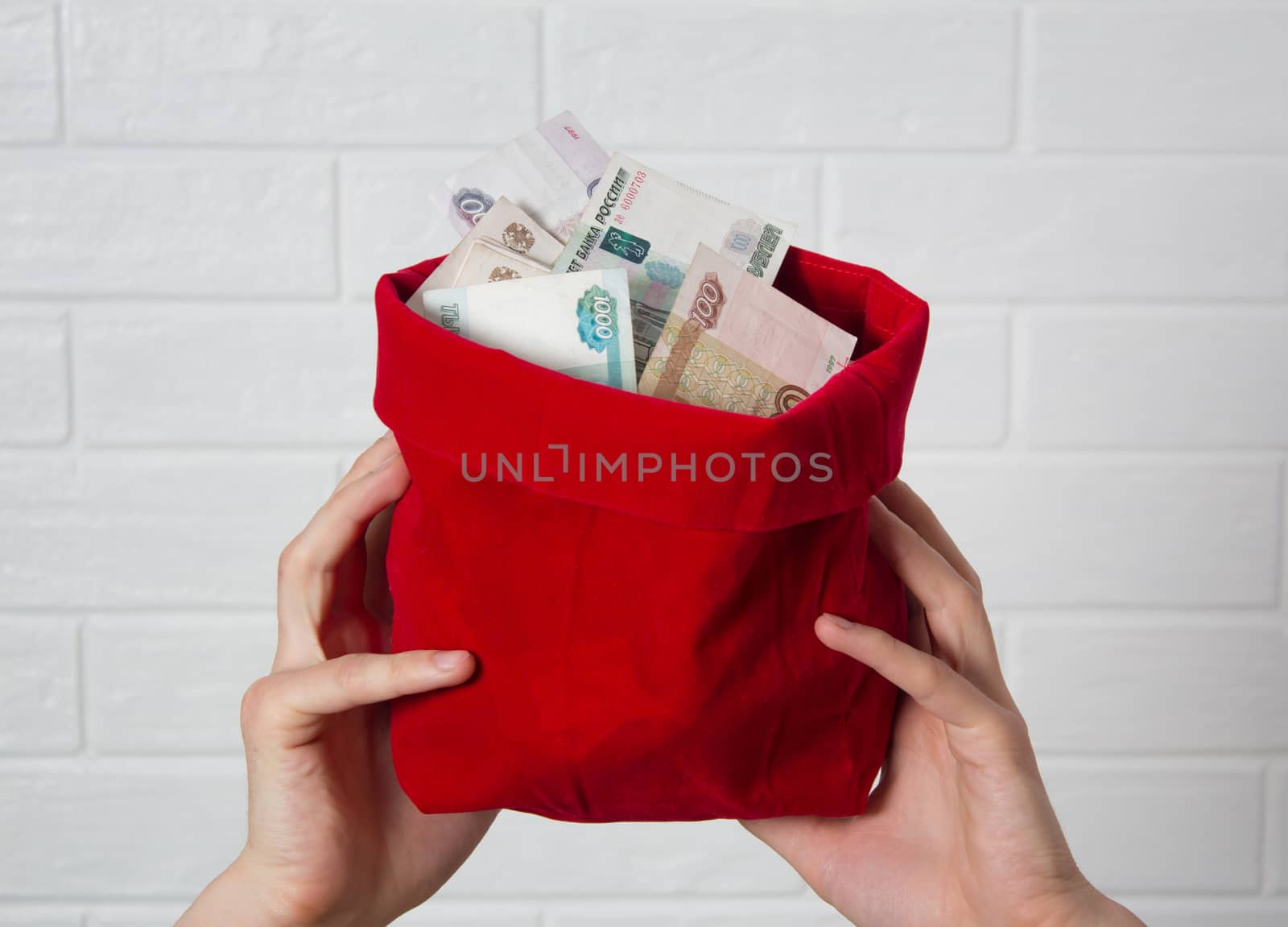 Hands holding a red bag with rubles. Much money. Banknote, the national currency of Russia. Bank, economy, business. Savings, salary, winnings, jackpot.