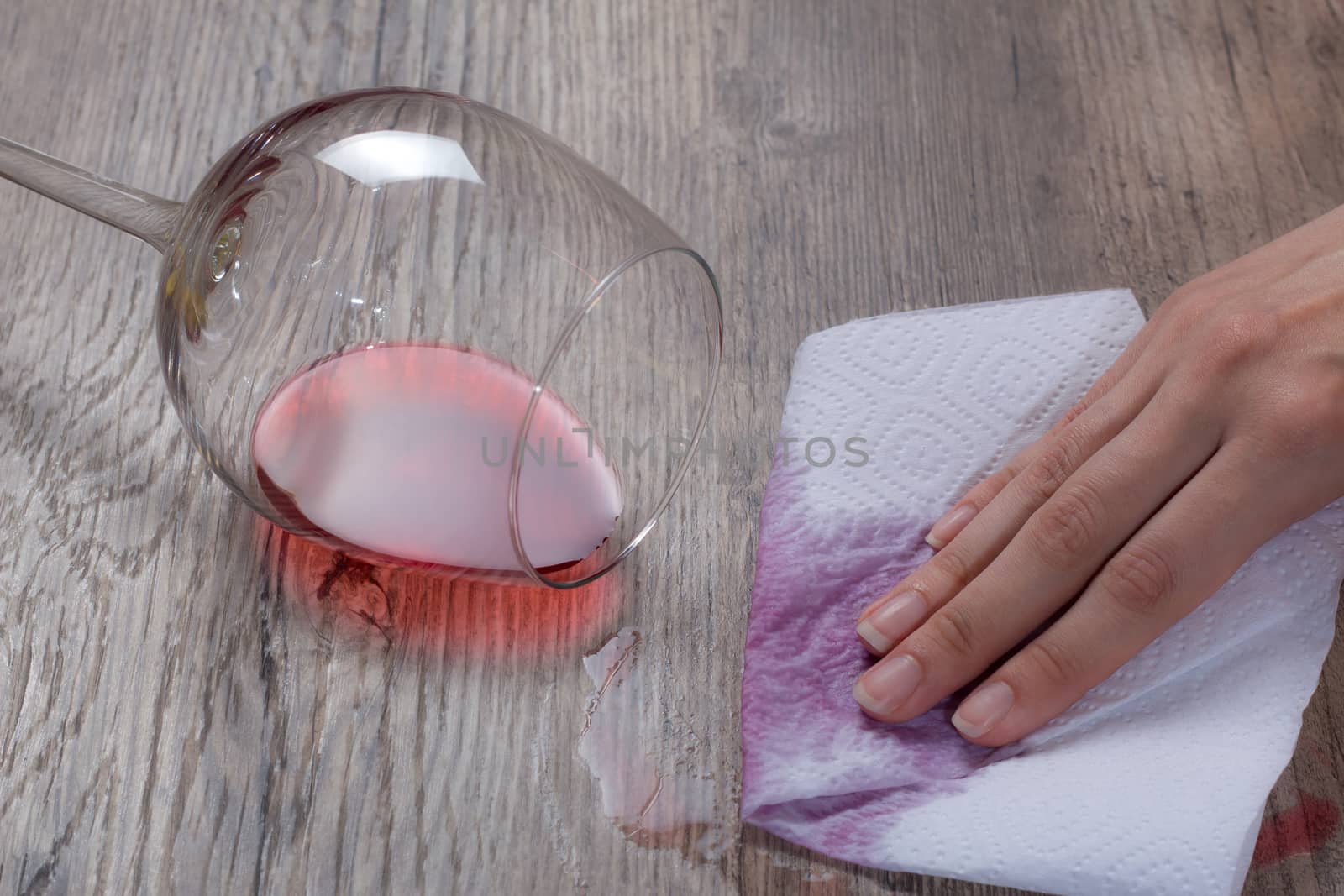 A woman wipes a wine stain with a paper napkin. The hand removes the spilled glass of wine. The woman does the cleaning. Clean, house, housekeeper, cleanup and housework.	