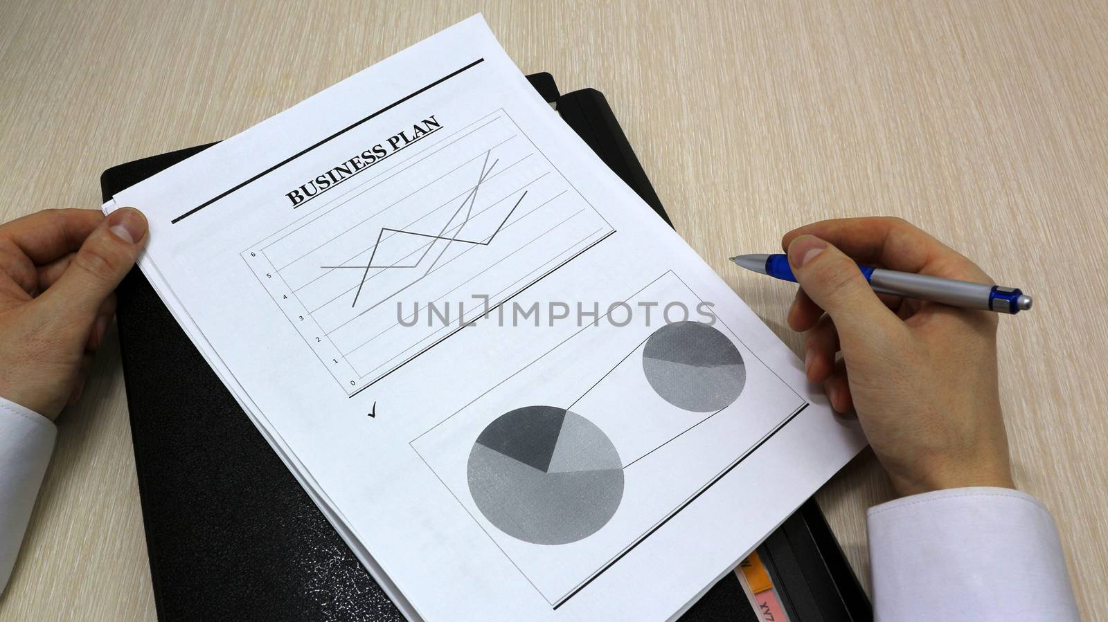 Job with finances in the office on a laptop,the employee holds paper with the inscription business plan.Businessman analyzes the chart of the rise or fall of prices and is a plan of action.businessman. businessman's working time	
