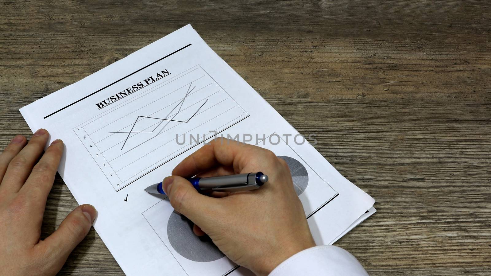  Job with finances in the office on a laptop,the employee holds paper with the inscription business plan.Businessman analyzes the chart of the rise or fall of prices and is a plan of action. market research	