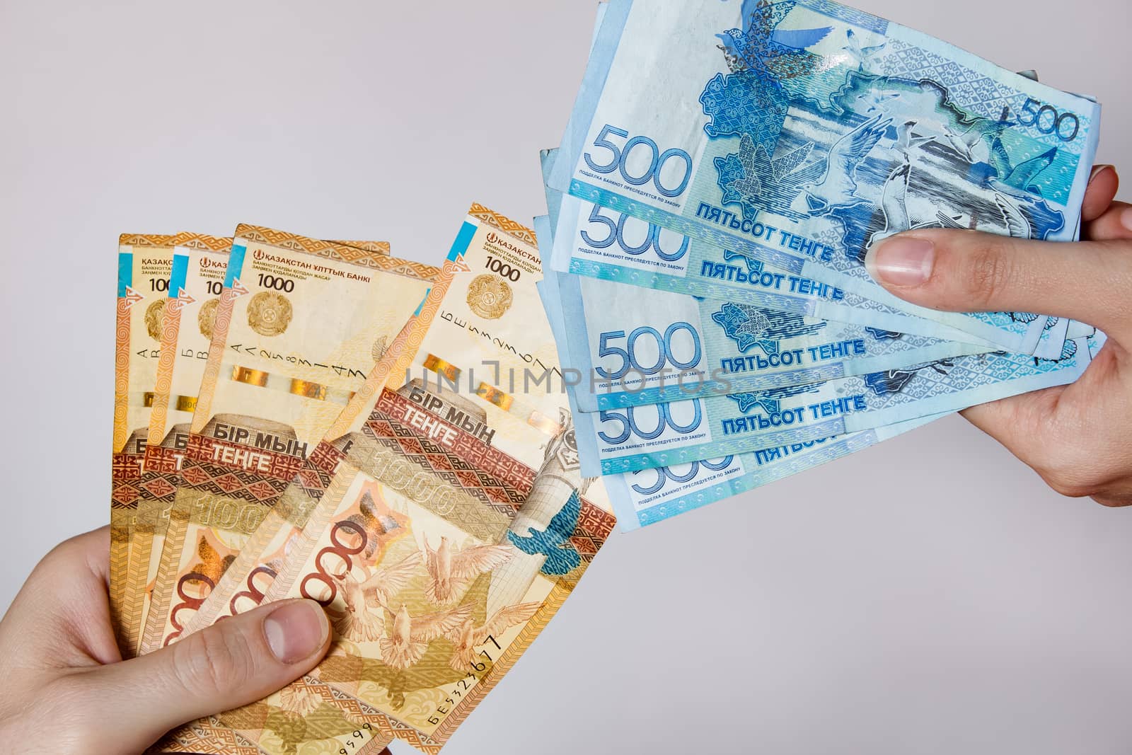 Paper banknotes tenge KZT people hold in their hands on white background. Tenge is the national currency of Kazakhstan.