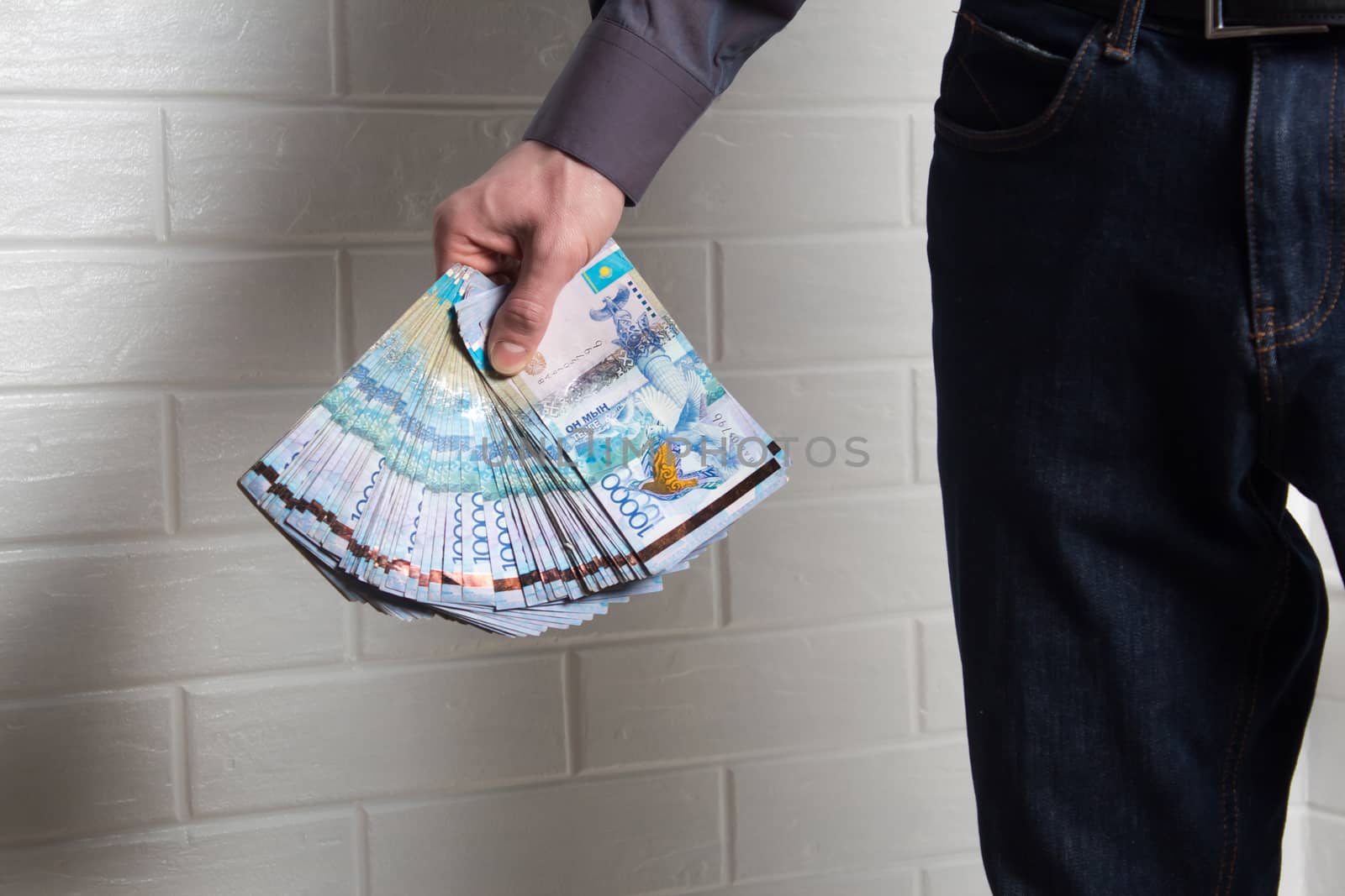 Guy holding money Tenge from the outside against a brick wall. Paper banknotes tenge KZT. Tenge is the national currency of Kazakhstan. bank of Kazakhstan