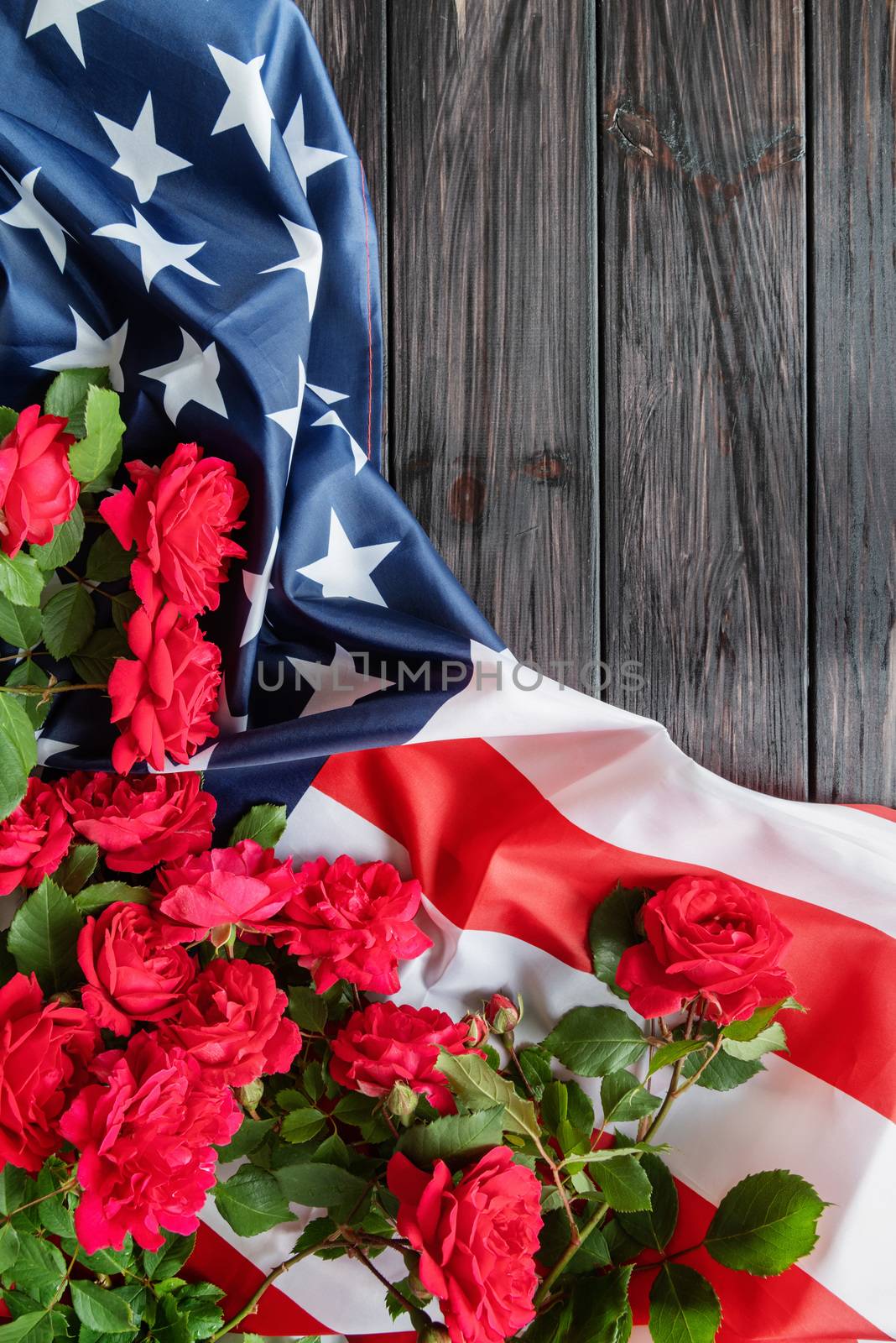 Red roses over the USA flag on dark wooden background top view flat lay by Desperada