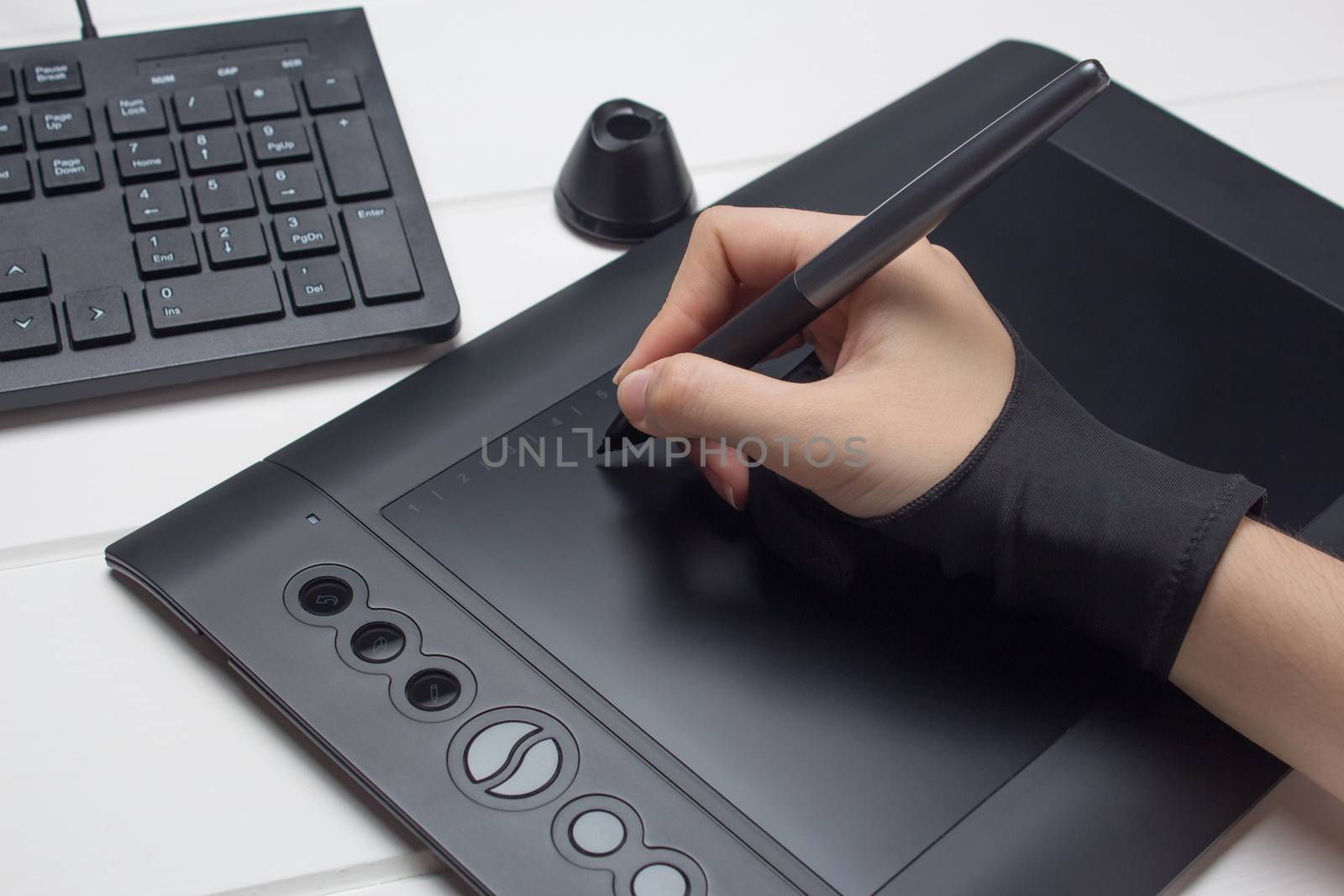 The hand draws on a graphics tablet. Freelance, designer, Illustrator. Technology, remote work, outsourcing. Glove and pen for a graphic tablet. Graphic designer working on digital tablet. Project