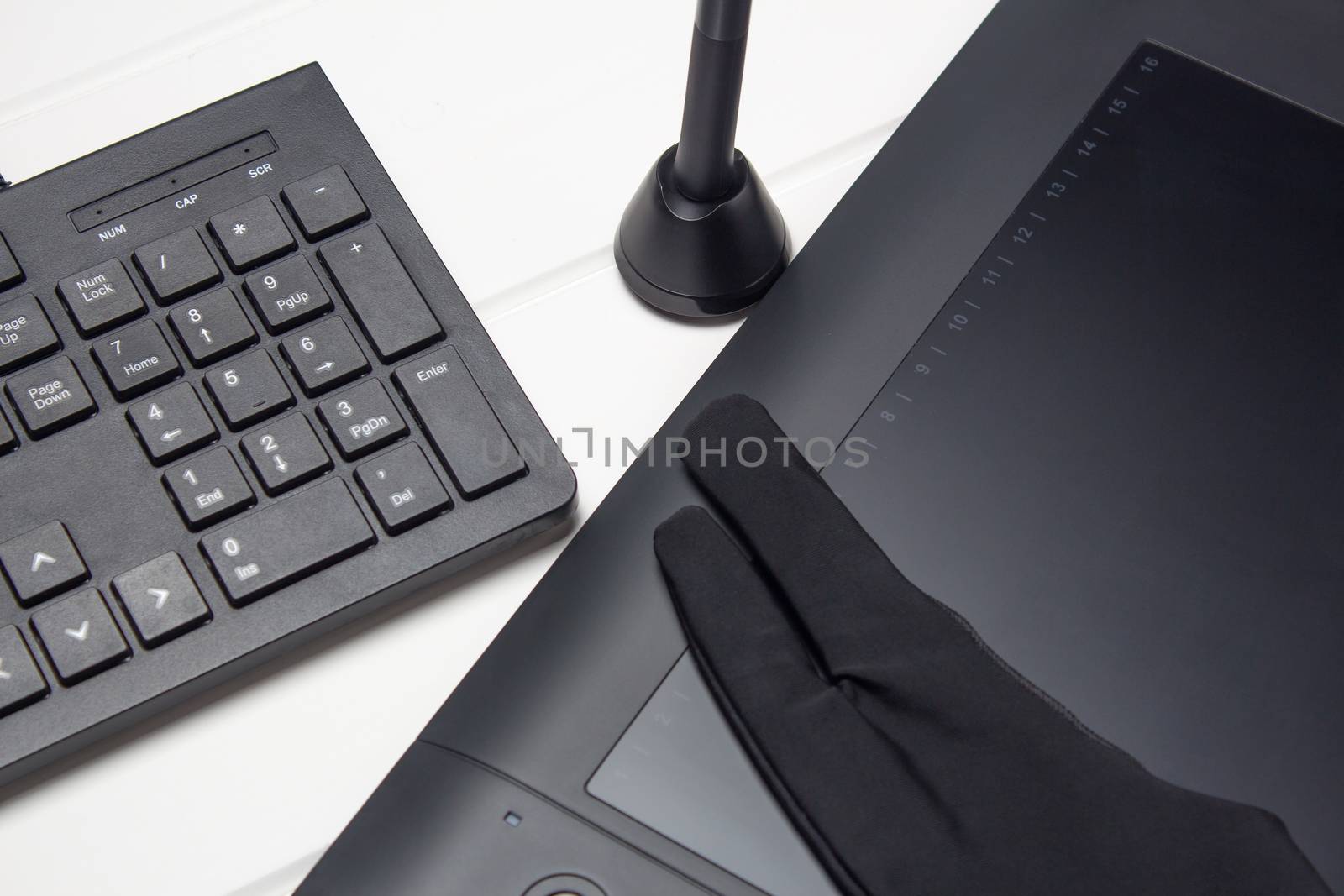 Graphic tablet, digital tablet and special pen, glove and keyboard on a white wooden table. Close-up, top view, flat lay. Freelance, designer, Illustrator. Technology, remote work, outsourcing. 