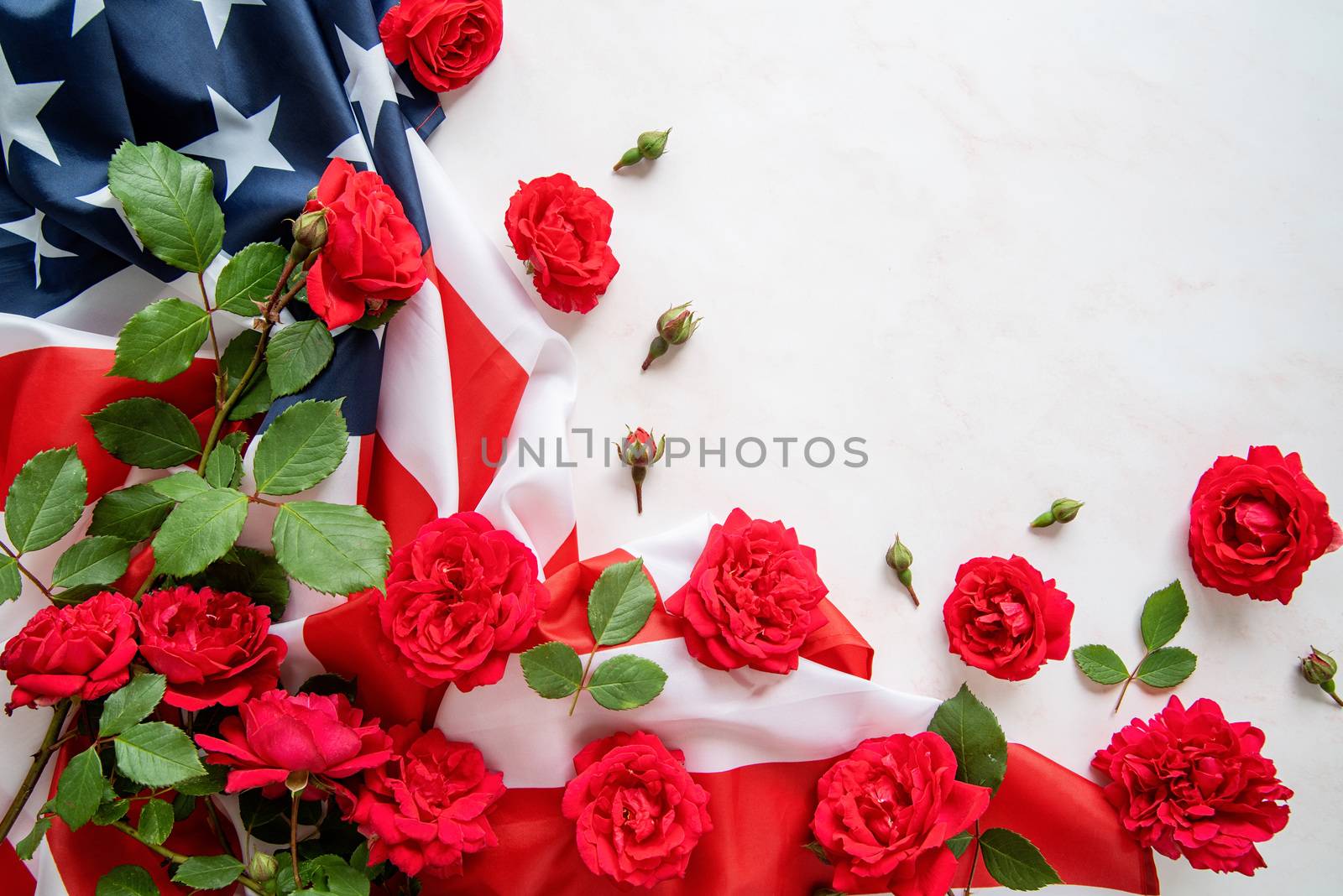 Independence Day USA concept. Memorial Day. Red roses over the USA flag top view flat lay with copy space