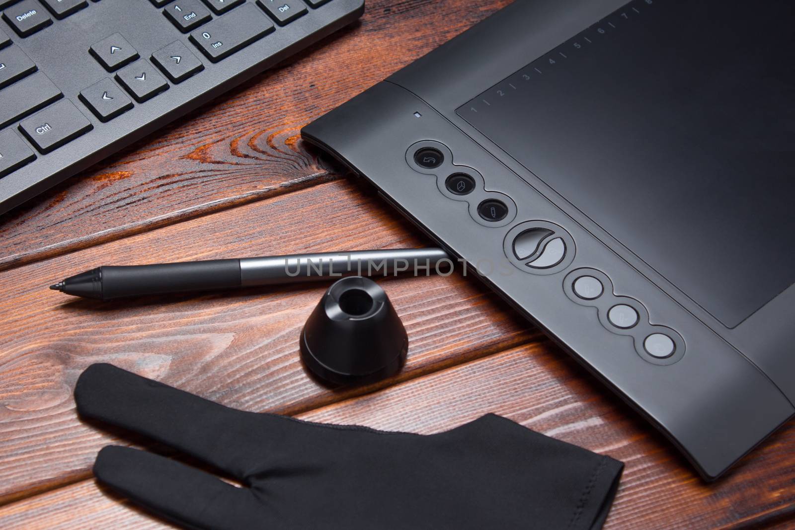 Graphic tablet, digital tablet and special pen, glove and keyboard on a wooden table. Close-up, top view, flat lay. Freelance, designer, Illustrator. Technology, remote work, outsourcing. creativity.