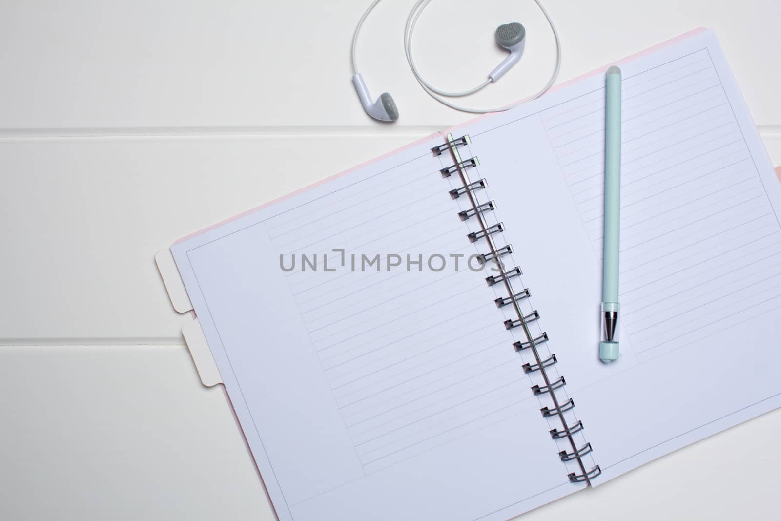 Daily planner on a white wooden background. Close-up, copy space, clear space, mockup. Clean sheet, flat lay, top view. Notepad, pen, headphones