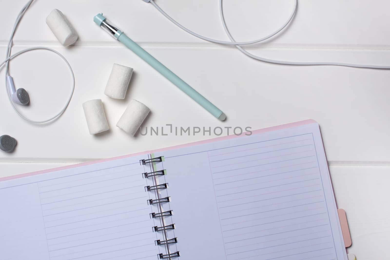 Daily planner on a white wooden background. Close-up, copy space, clear space, mockup. Clean sheet, flat lay, top view. Notepad, pen, headphones, to-do list, marshmallow