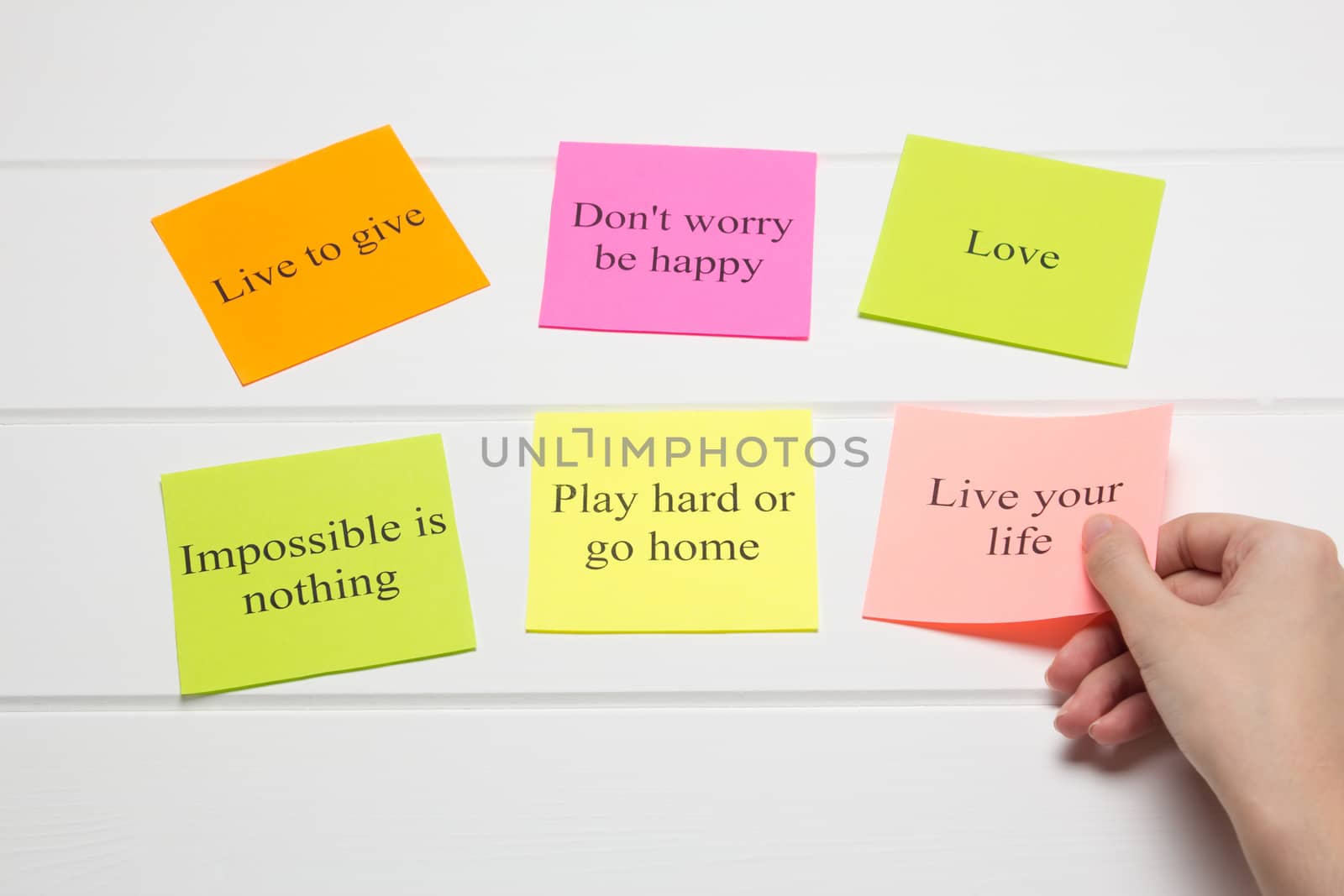 The hand lays out motivational cards. Color sheets with quotes. Visualization Board, self-discipline, development, training. Flat lay, top view. plan, strategy, concept, future.