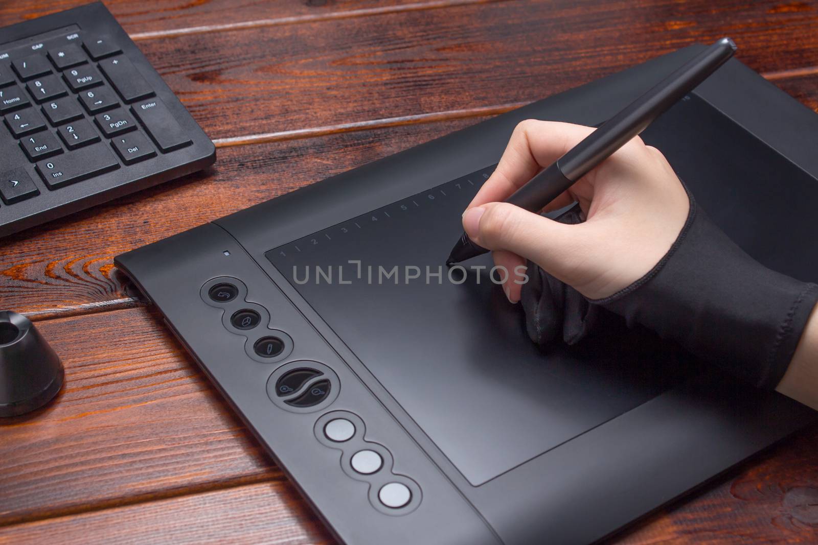 The hand draws on a graphics tablet. Freelance, designer, Illustrator. Technology, remote work, outsourcing. Glove and pen for a graphic tablet. Graphic designer working on digital tablet. Project, co