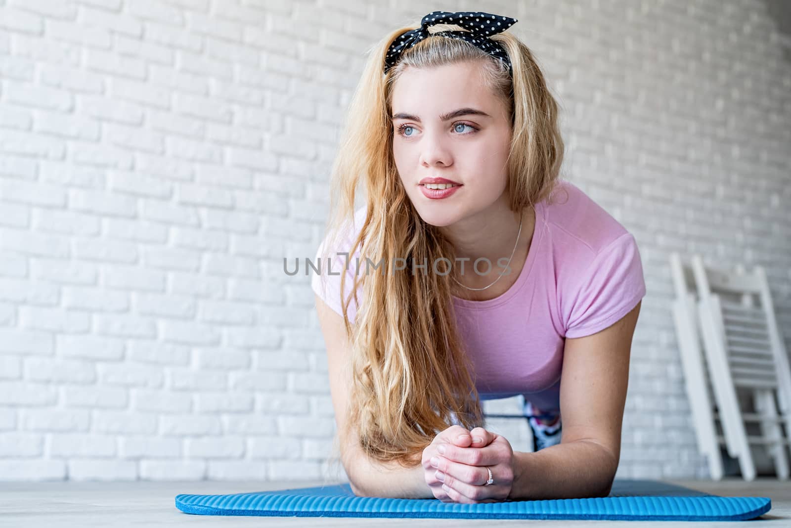 Fitness, sport, training and lifestyle concept. Athletic woman exercising on a fitness mat at home at white brick wall background with copy space