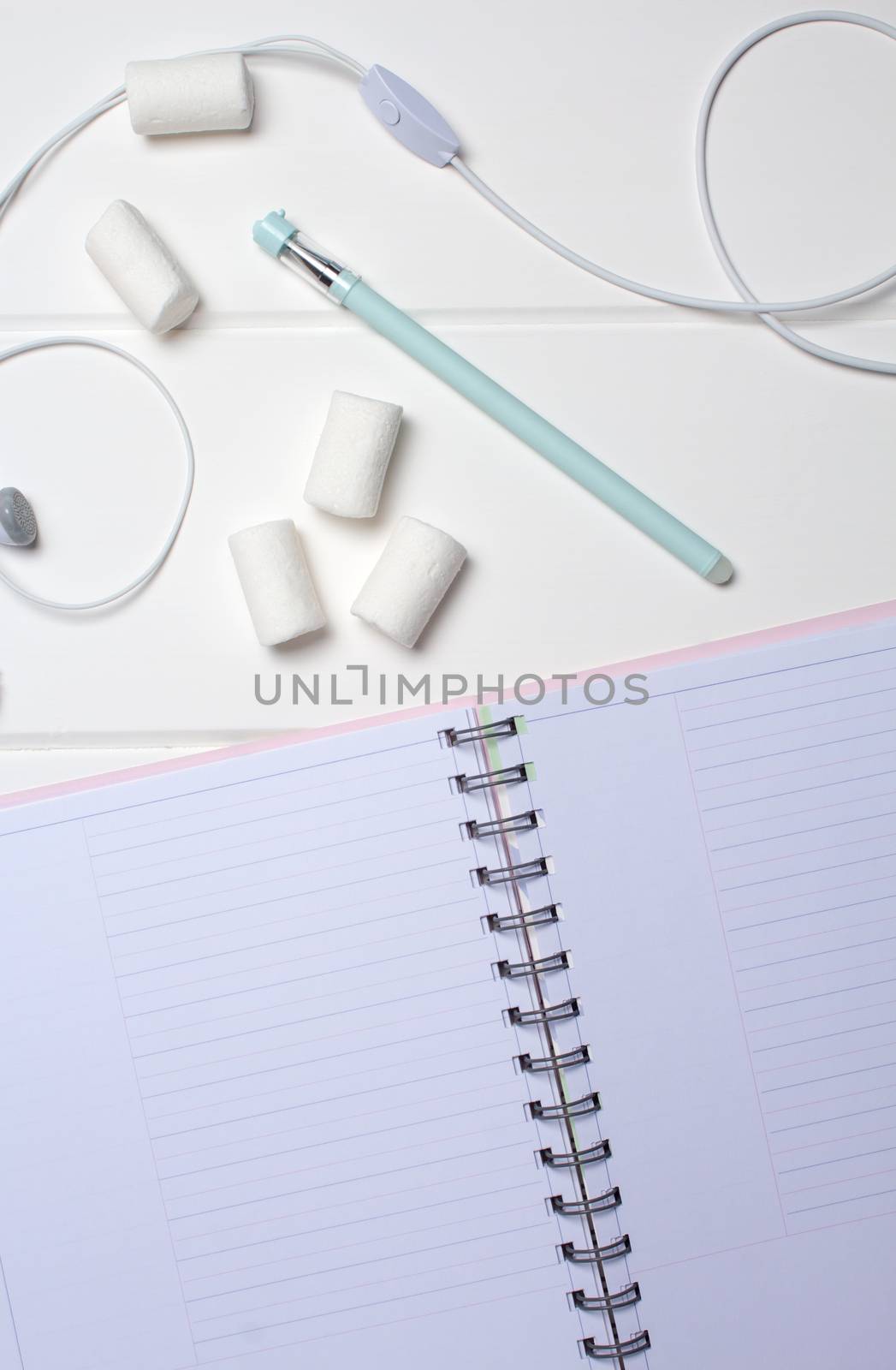 Daily planner on a white wooden background. Close-up, copy space, clear space, mockup. Clean sheet, flat lay, top view. Notepad, pen, headphones, to-do list, marshmallow