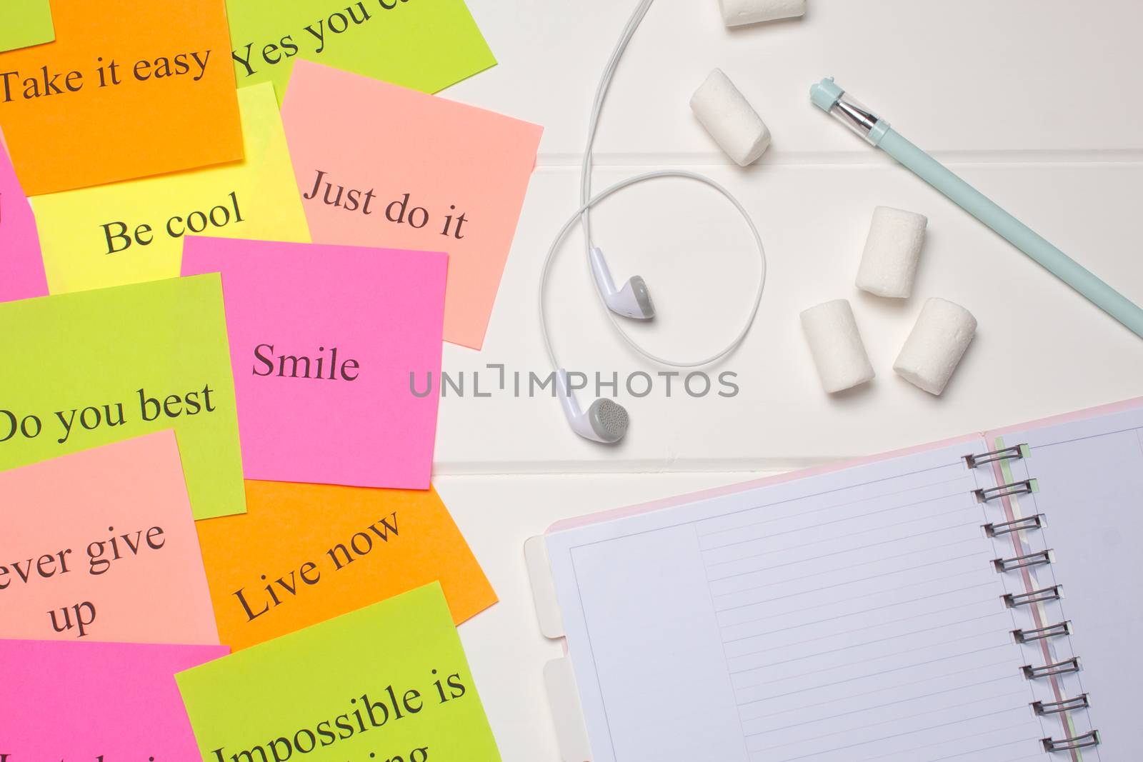 Daily planner, pen, headphones, and colorful word cards. Close-up on a white background. Copy space. Clean sheet, flat lay, top view.  To-do list, marshmallow. Color sheets with quotes. Visualization 