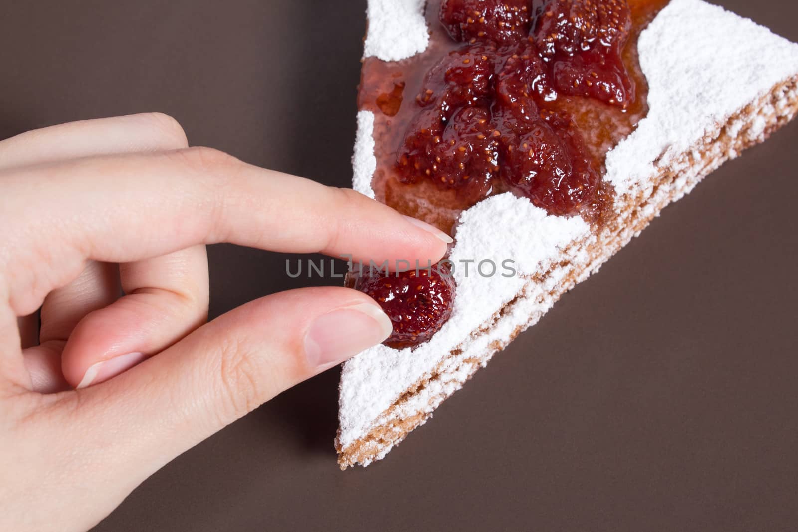 Hand holding a piece of cake with strawberry jam and sugar. Dessert, food, sweet, baking. Biscuit, brownie, tiramisu, cheesecake. Cook at home, homemade, closeup, Bakery products.