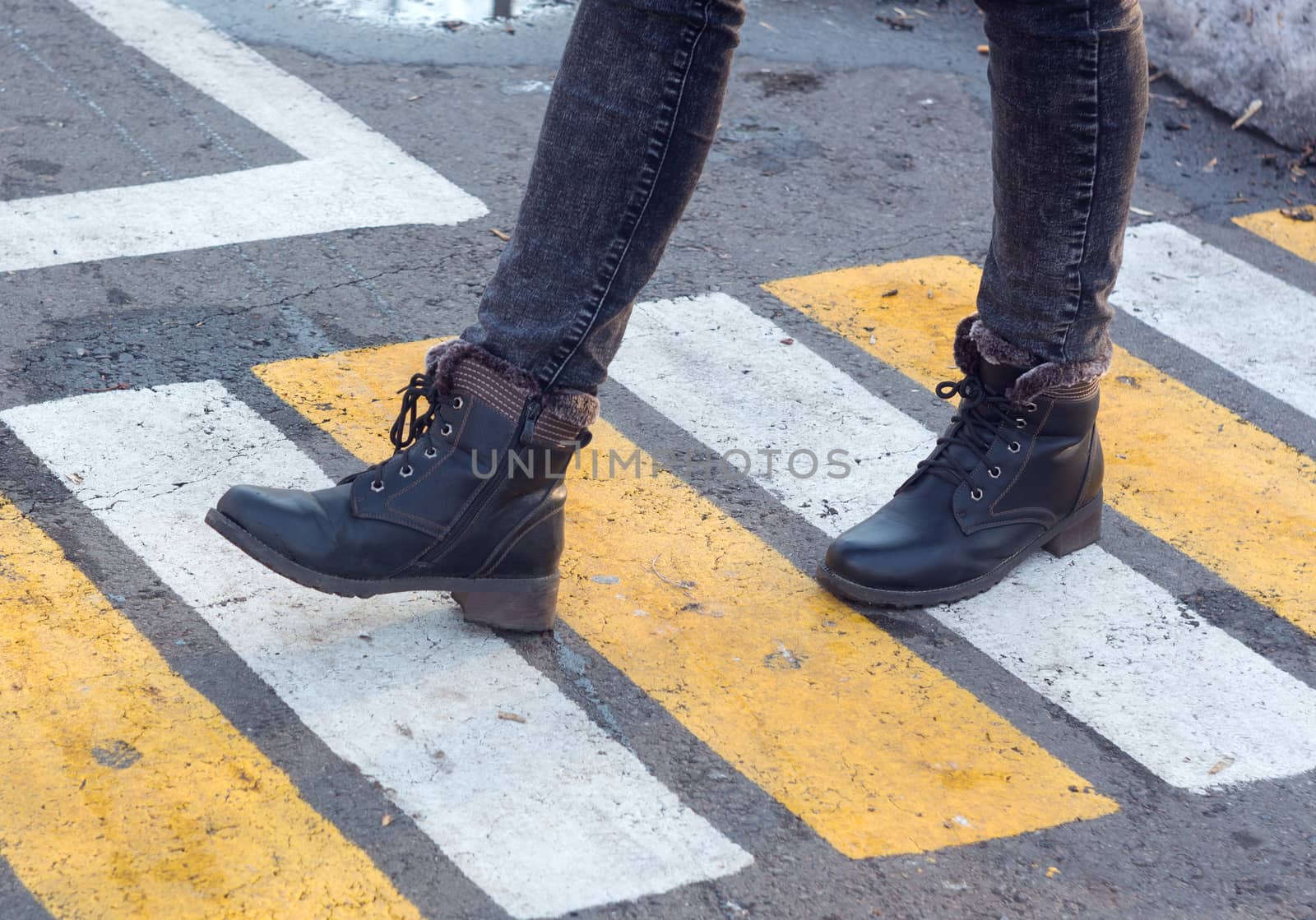 Women's feet on a pedestrian crossing. Shoes, boots, go, walk. Asphalt, markings, mud, puddles. Autumn, slush, spring. Close up. Casual