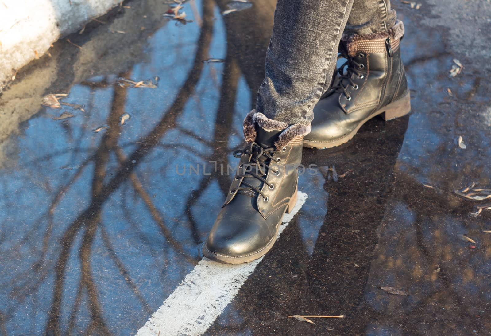 Women's feet in a puddle. Shoes, boots, go, walk. Asphalt, markings, dirt. Autumn, slush, spring. Close up. Casual