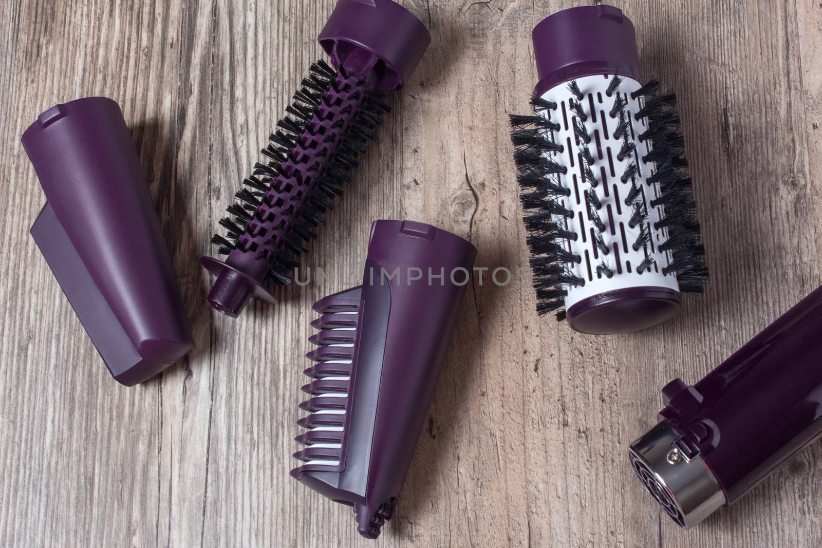 Set of hair dryer attachments on a wooden background. Curling iron, hair straightener. Hot styling, boar bristles, hair care. Beauty salon, styling, haircut. Beauty, fashion, style.