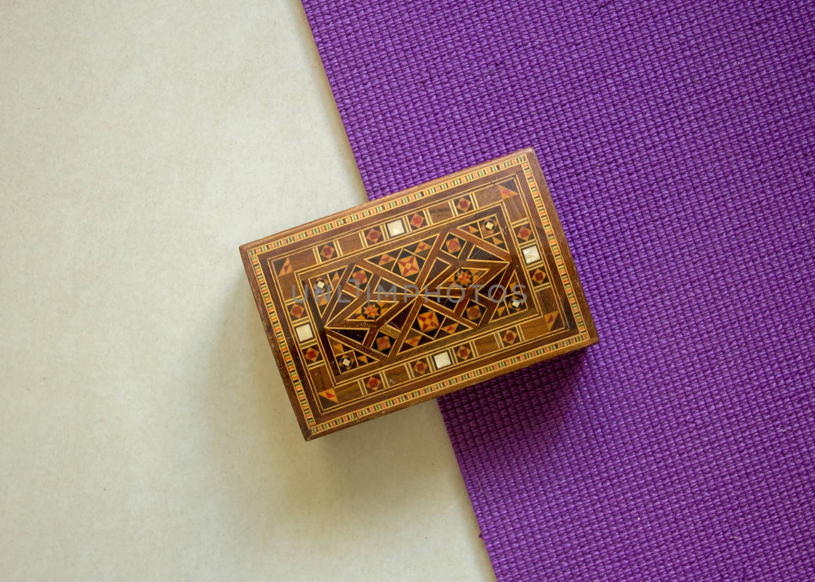 Top view of a wooden box very well ornamented with small bamboo pieces, with a white and purple background
