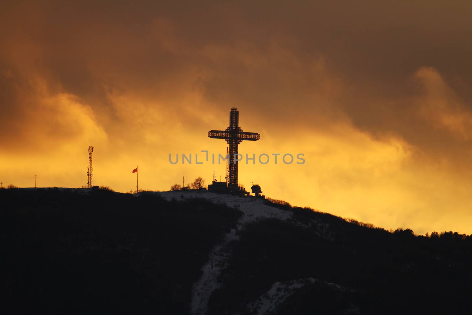 Orthodox cross in the mountains, sunset clouds