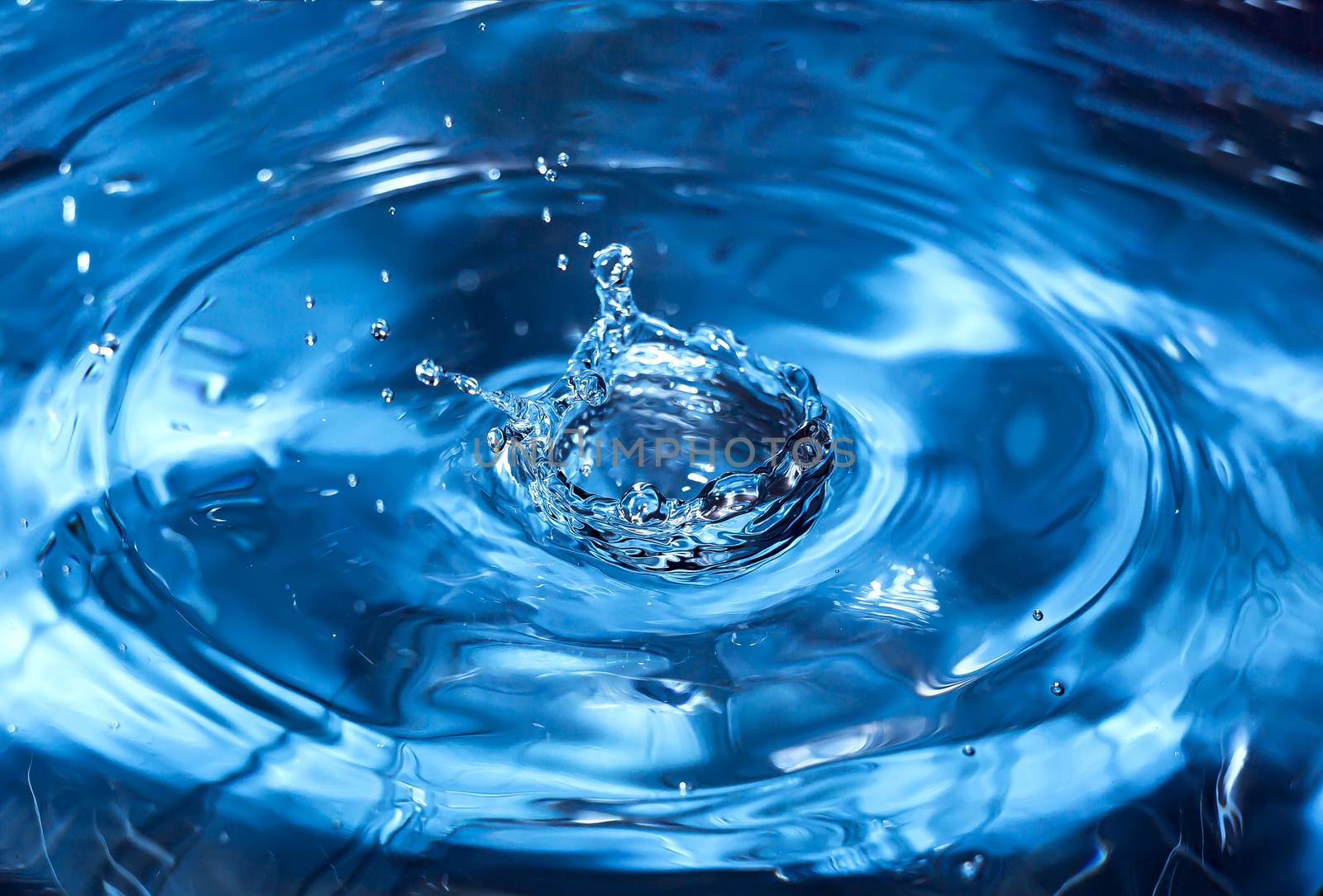 Water splash close-up. Drop of water. Blue water drop. Falling blue water surface with splash and air bubbles