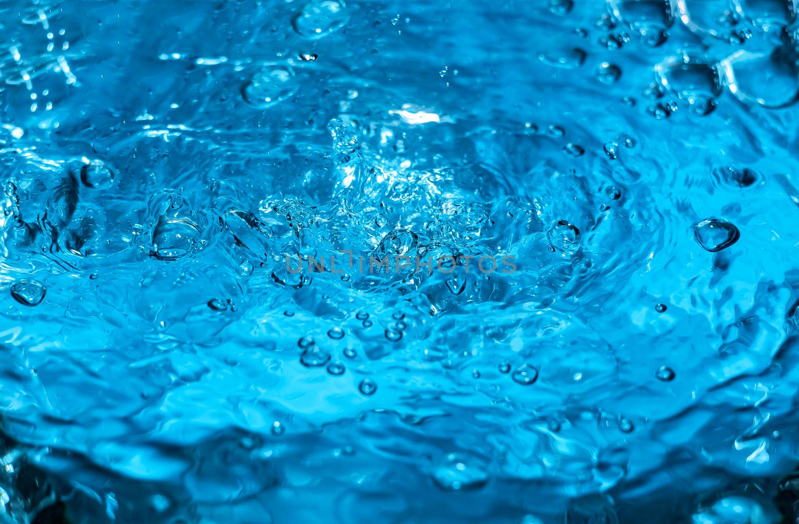 Water splash close-up. Drop of water. Blue water drop. Falling blue water surface with splash and air bubbles
