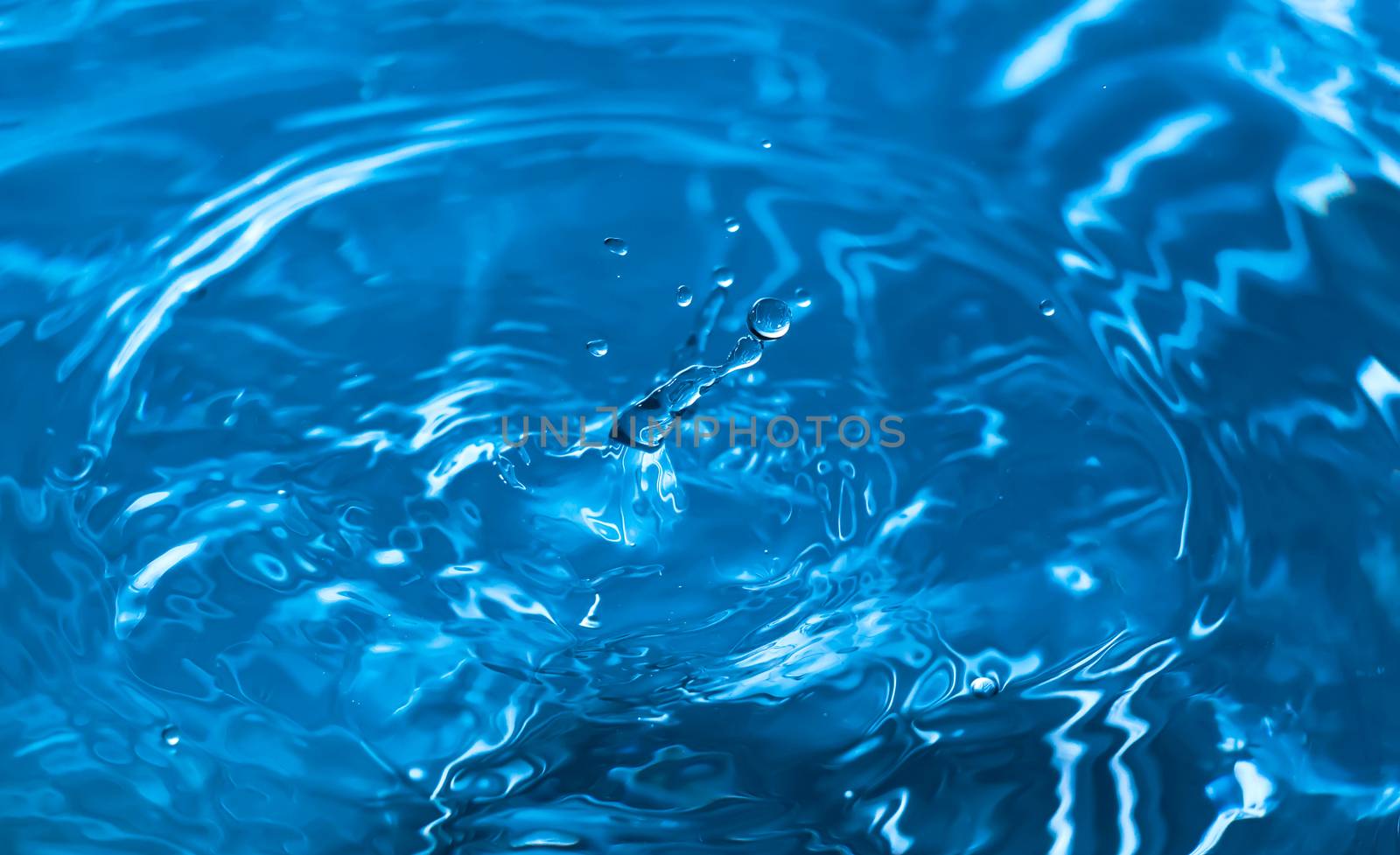 Water splash close-up. Drop of water. Blue water drop. Falling blue water surface with splash and air bubbles.