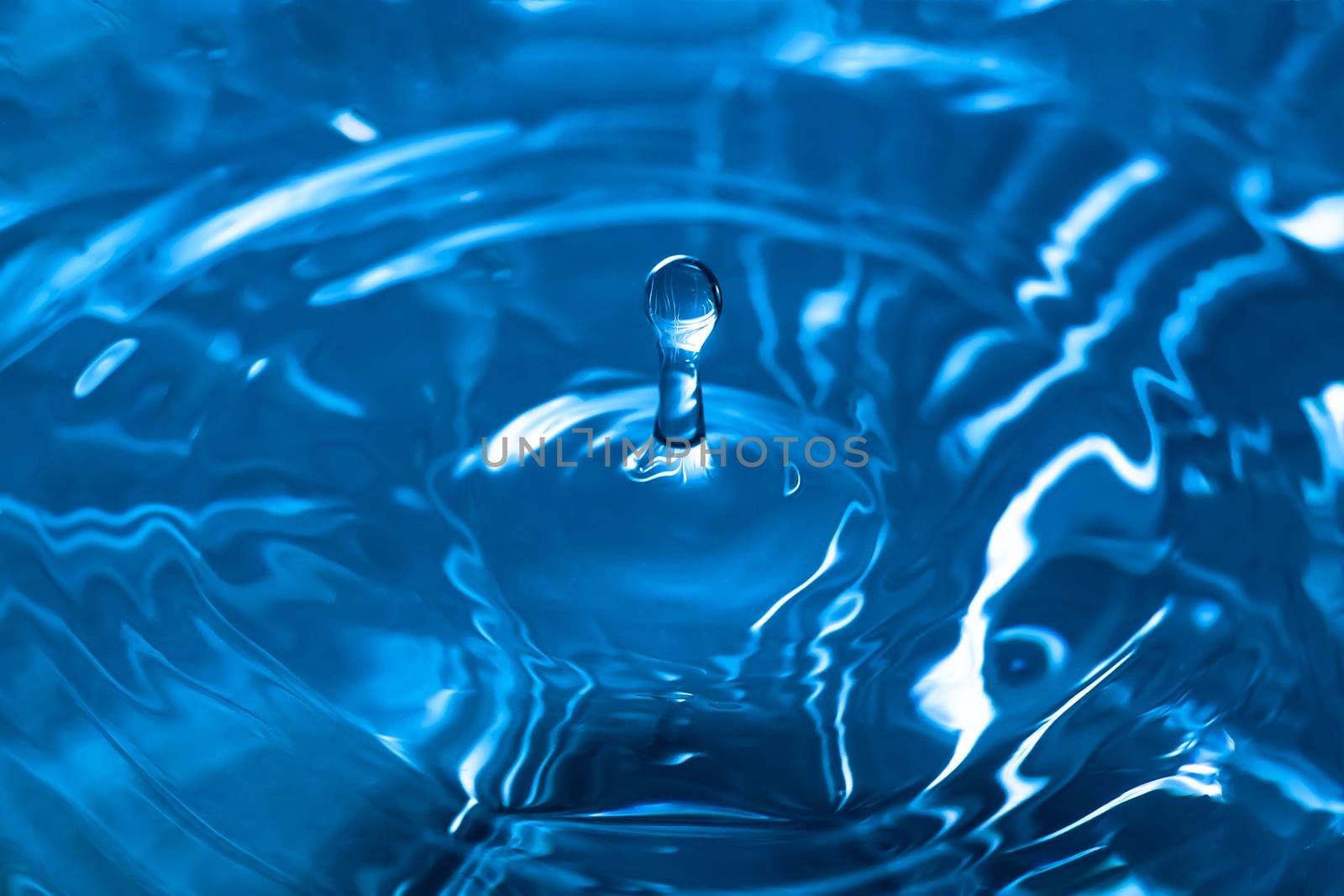 Water splash close-up. Drop of water. Blue water drop. Falling blue water surface with splash and air bubbles.