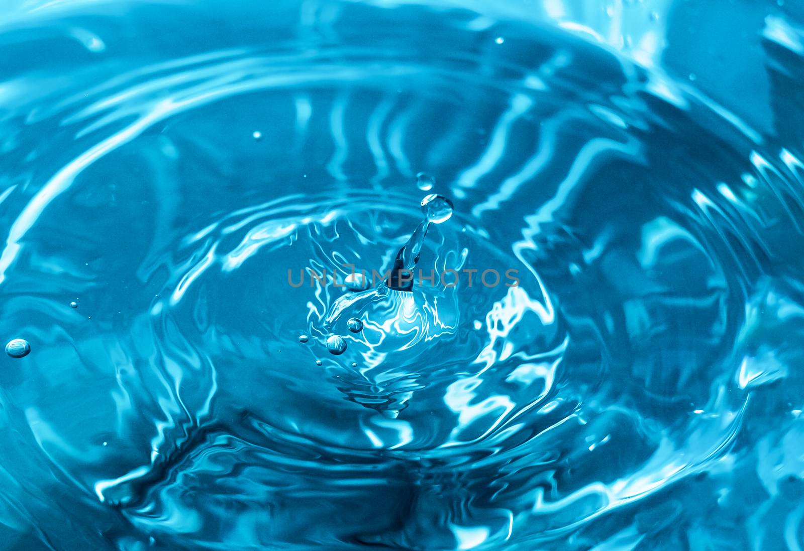 Water splash close-up. Drop of water. Blue water drop. Falling blue water surface with splash and air bubbles