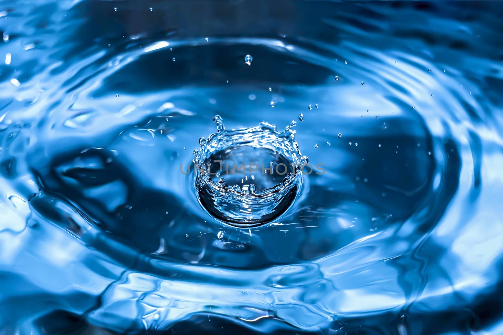 Water splash close-up. Drop of water. Blue water drop. Falling blue water surface with splash and air bubbles