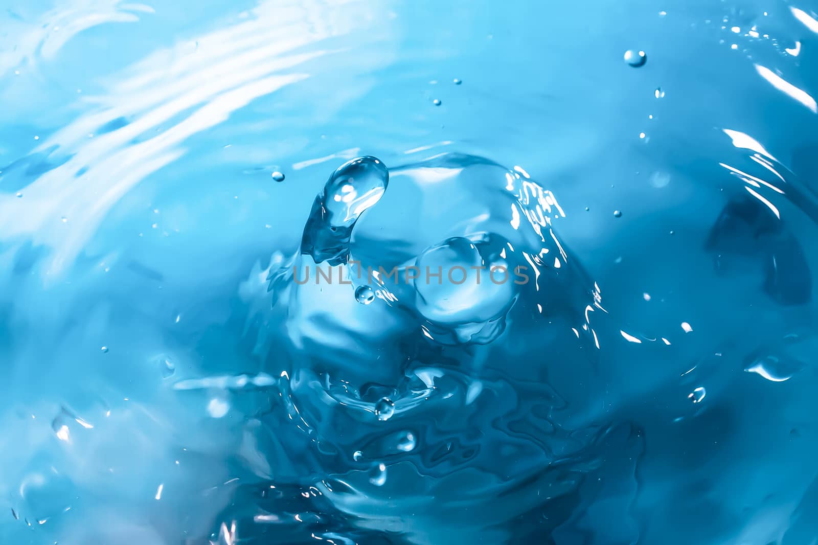 Water splash close-up. Drop of water. Blue water drop. Falling blue water surface with splash and air bubbles