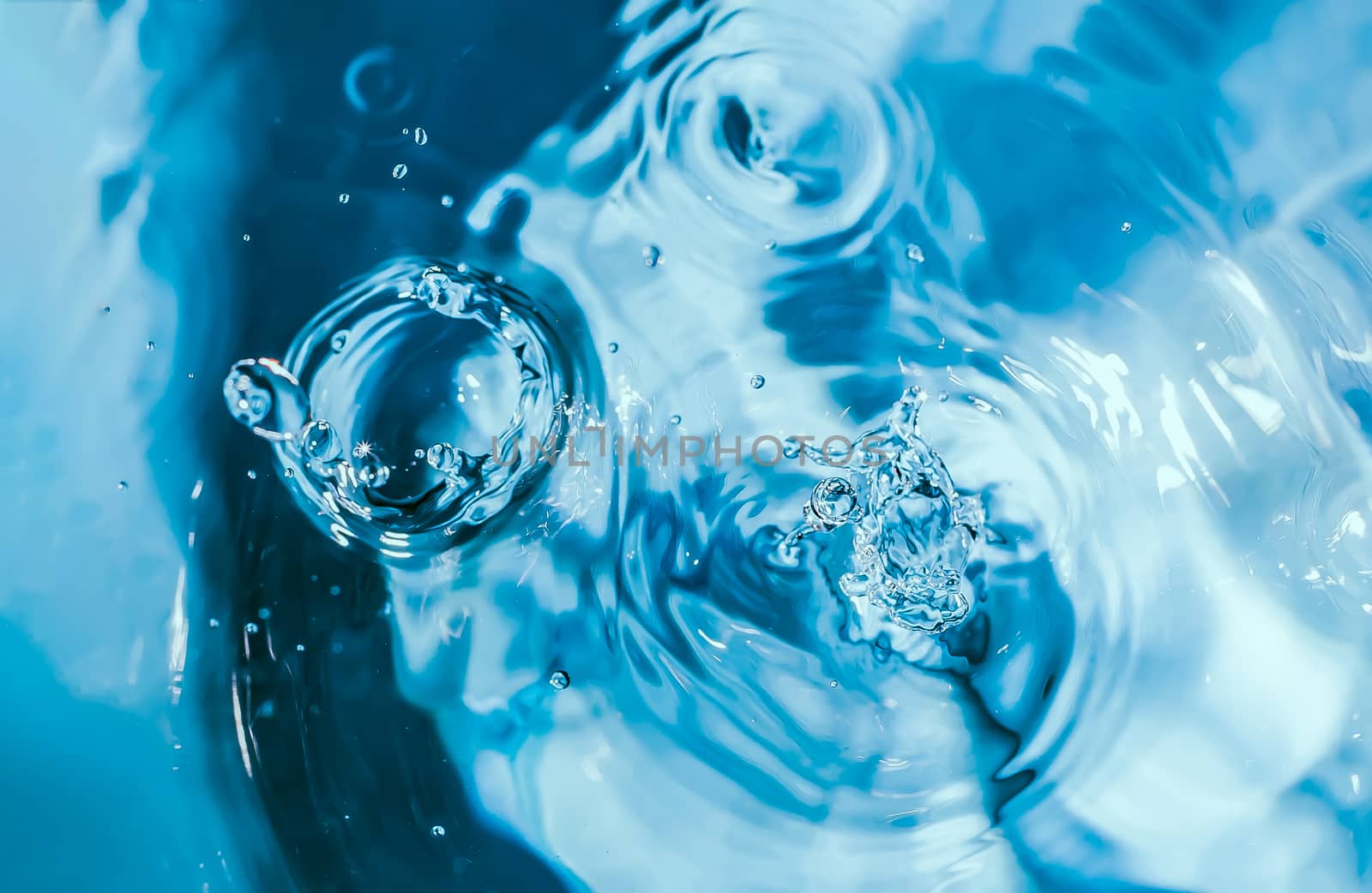 Water splash close-up. Drop of water. Blue water drop. Falling blue water surface with splash and air bubbles