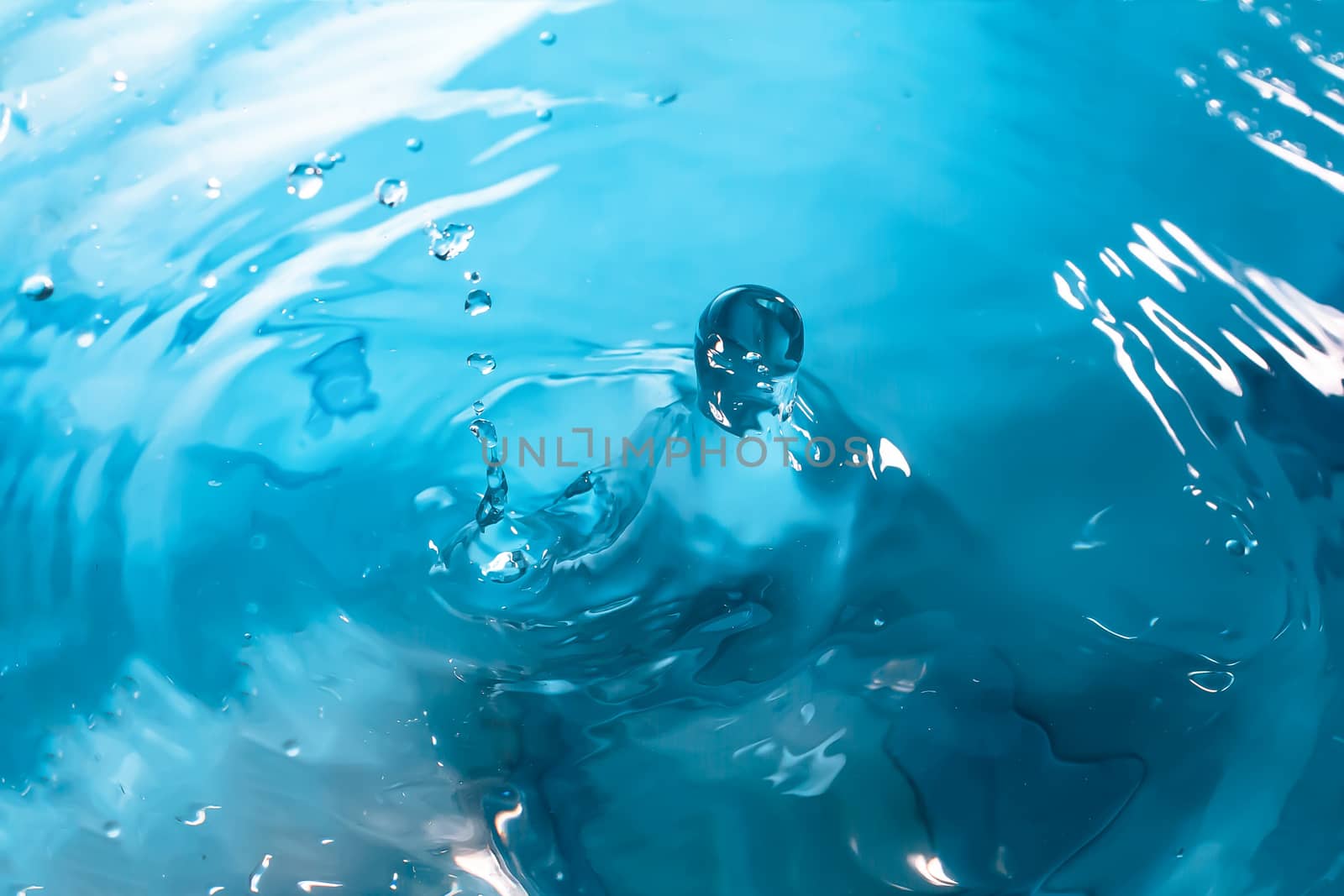 Water splash close-up. Drop of water. Blue water drop. Falling blue water surface with splash and air bubbles