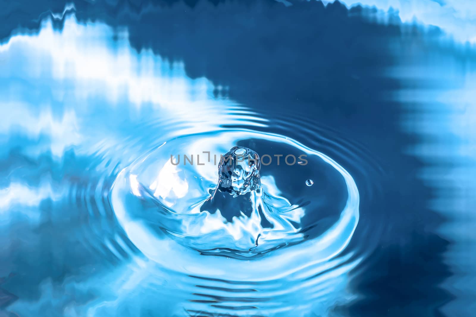 Water splash close-up. Drop of water. Blue water drop. Falling blue water surface with splash and air bubbles