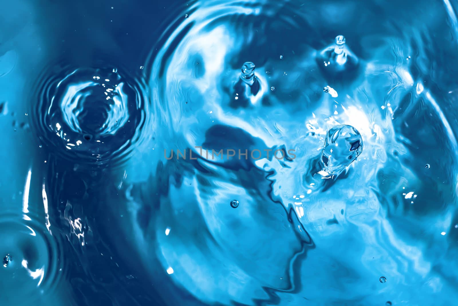 Water splash close-up. Drop of water. Blue water drop. Falling blue water surface with splash and air bubbles