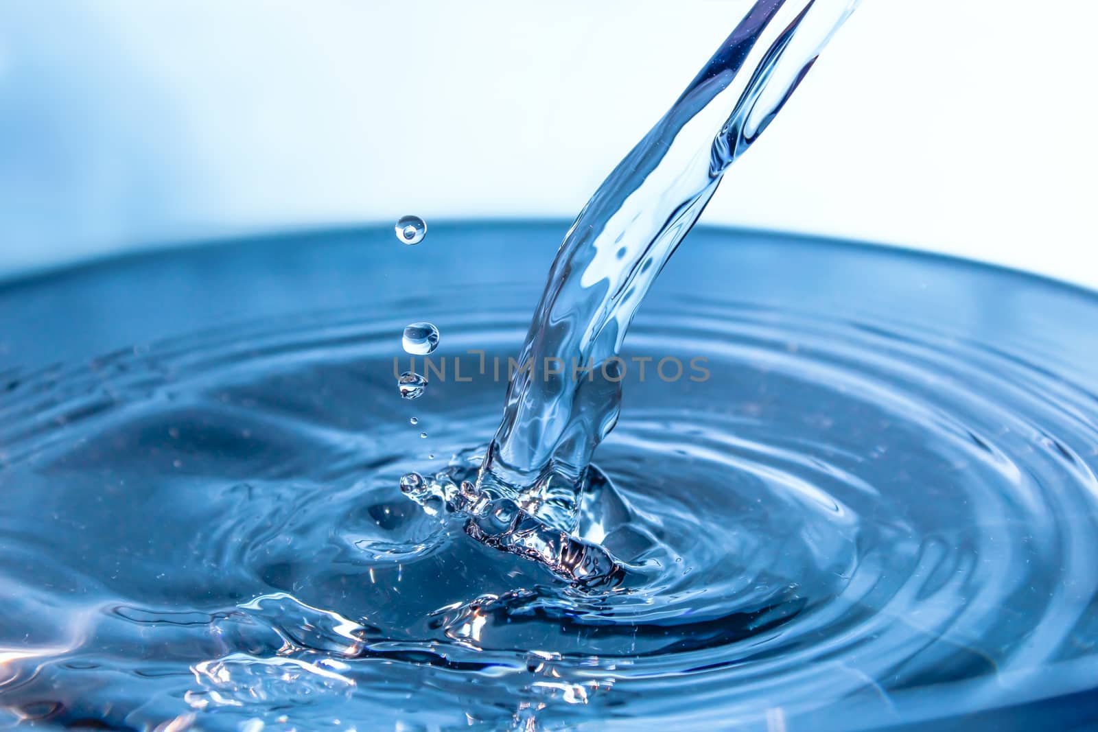 Water splash close-up. Drop of water. Blue water drop. Falling blue water surface with splash and air bubbles