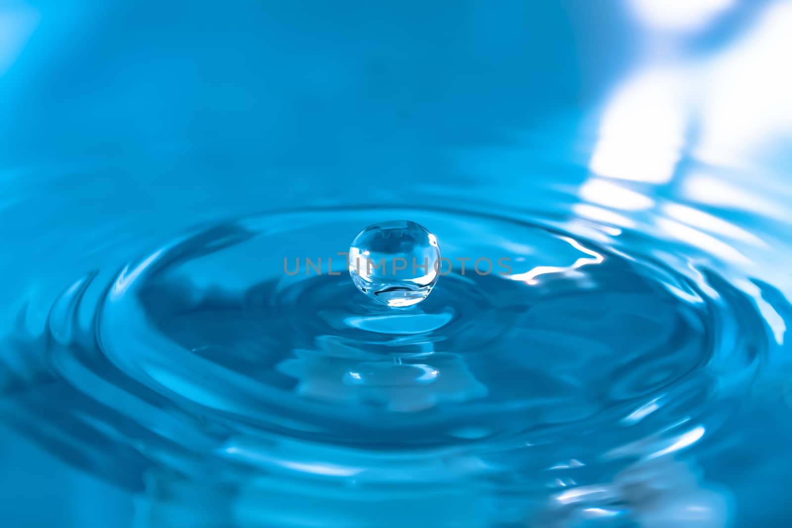 Water splash close-up. Drop of water. Blue water drop. Falling blue water surface with splash and air bubbles