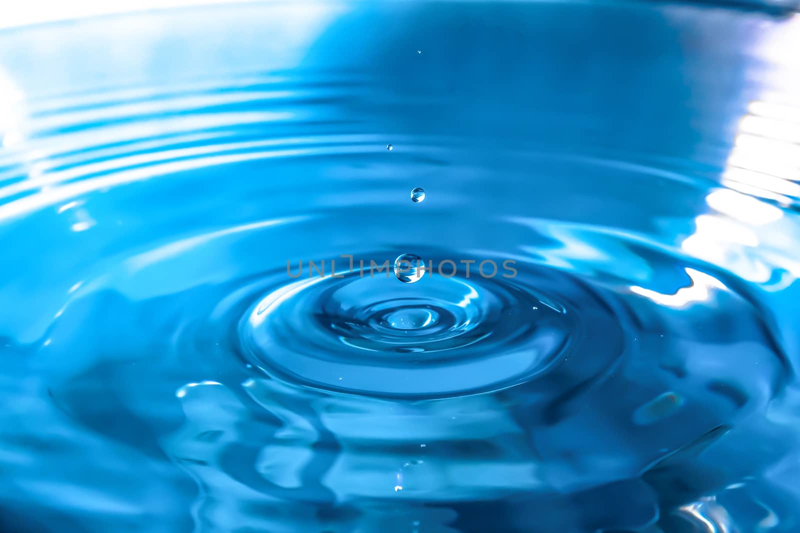 Water splash close-up. Drop of water. Blue water drop. Falling blue water surface with splash and air bubbles