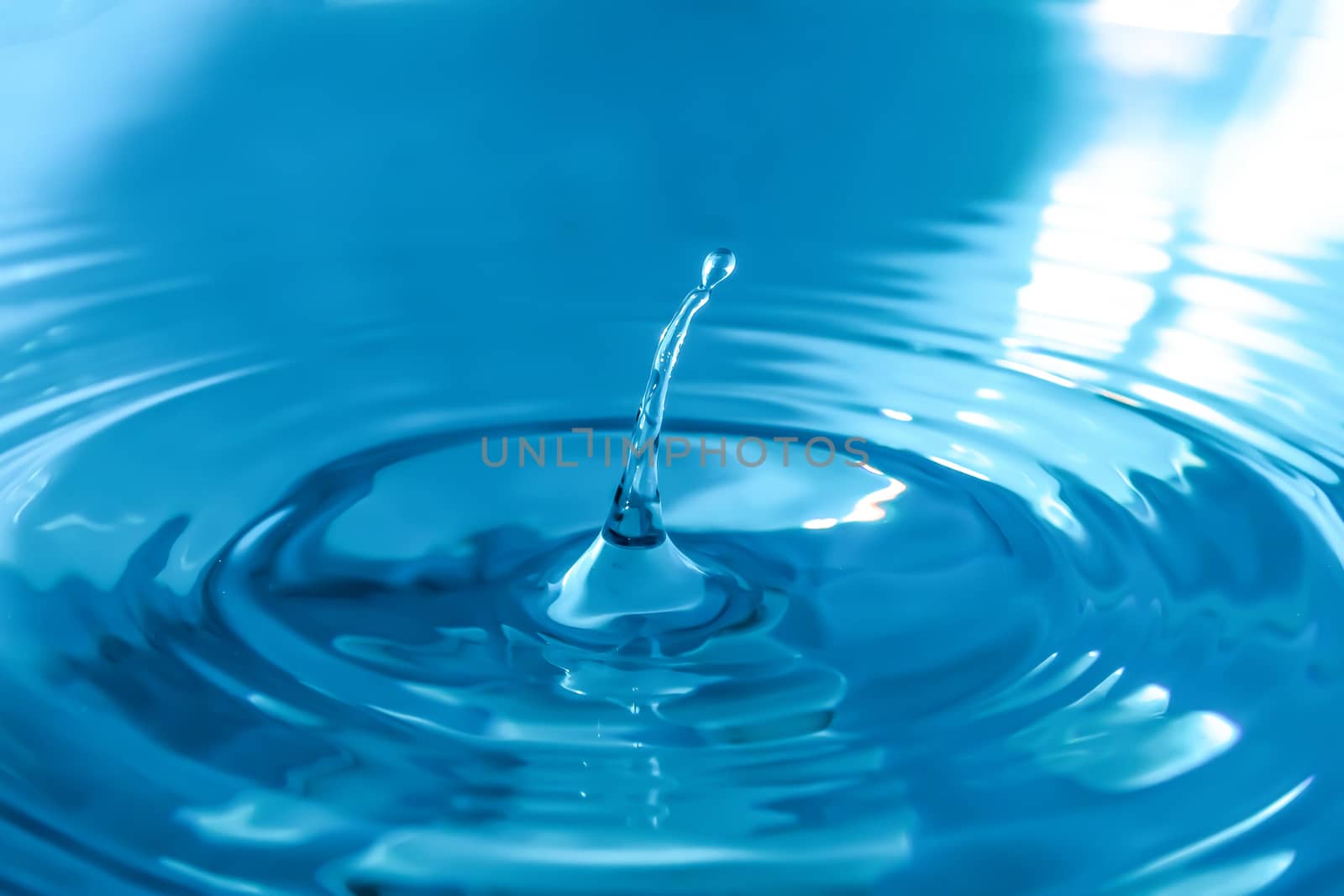 Water splash close-up. Drop of water. Blue water drop. Falling blue water surface with splash and air bubbles