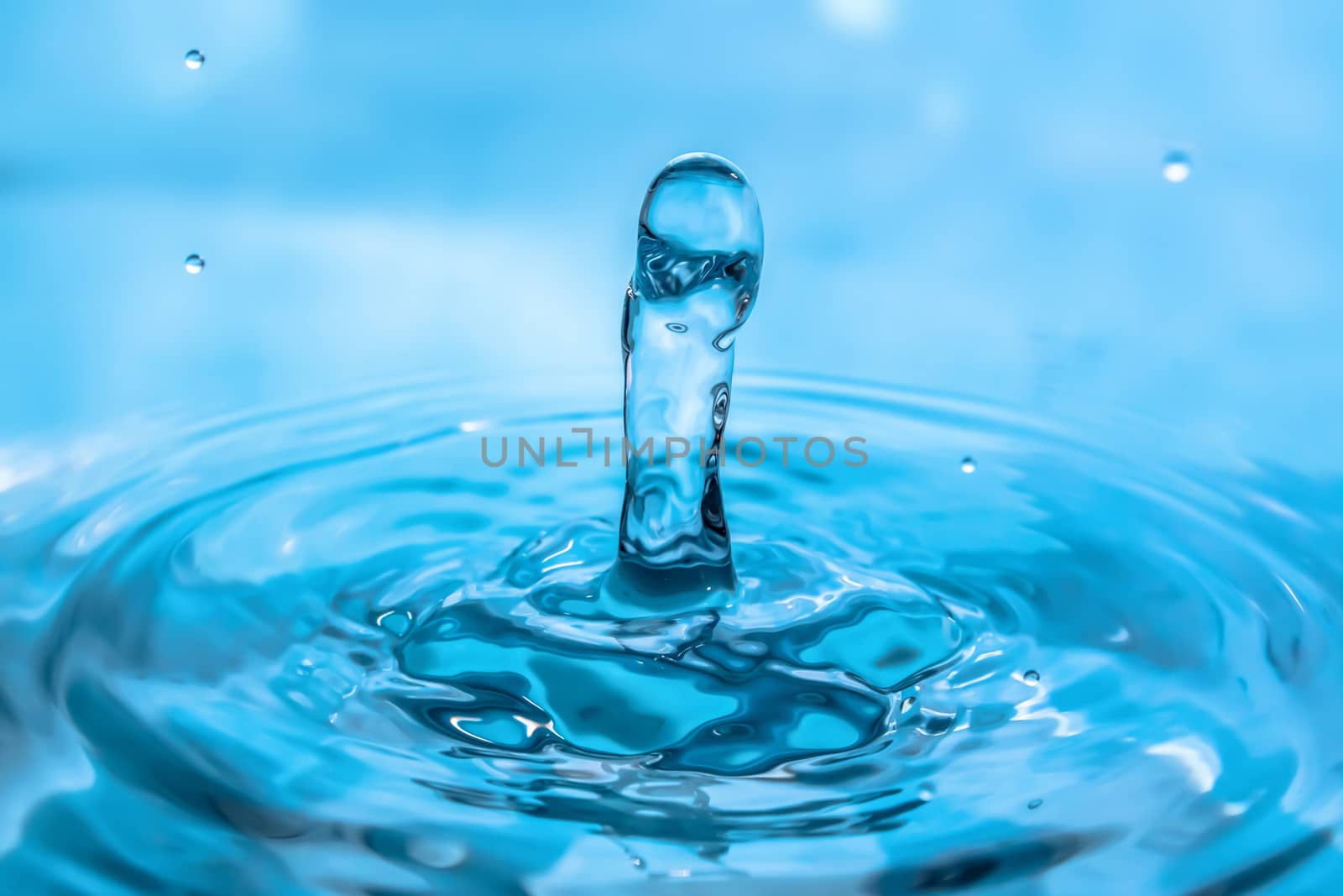 Water splash close-up. Drop of water. Blue water drop. Falling blue water surface with splash and air bubbles