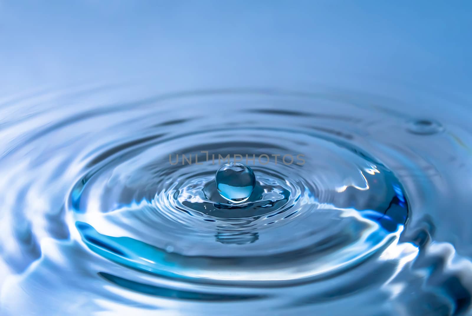 Water splash close-up. Drop of water. Blue water drop. Falling blue water surface with splash and air bubbles