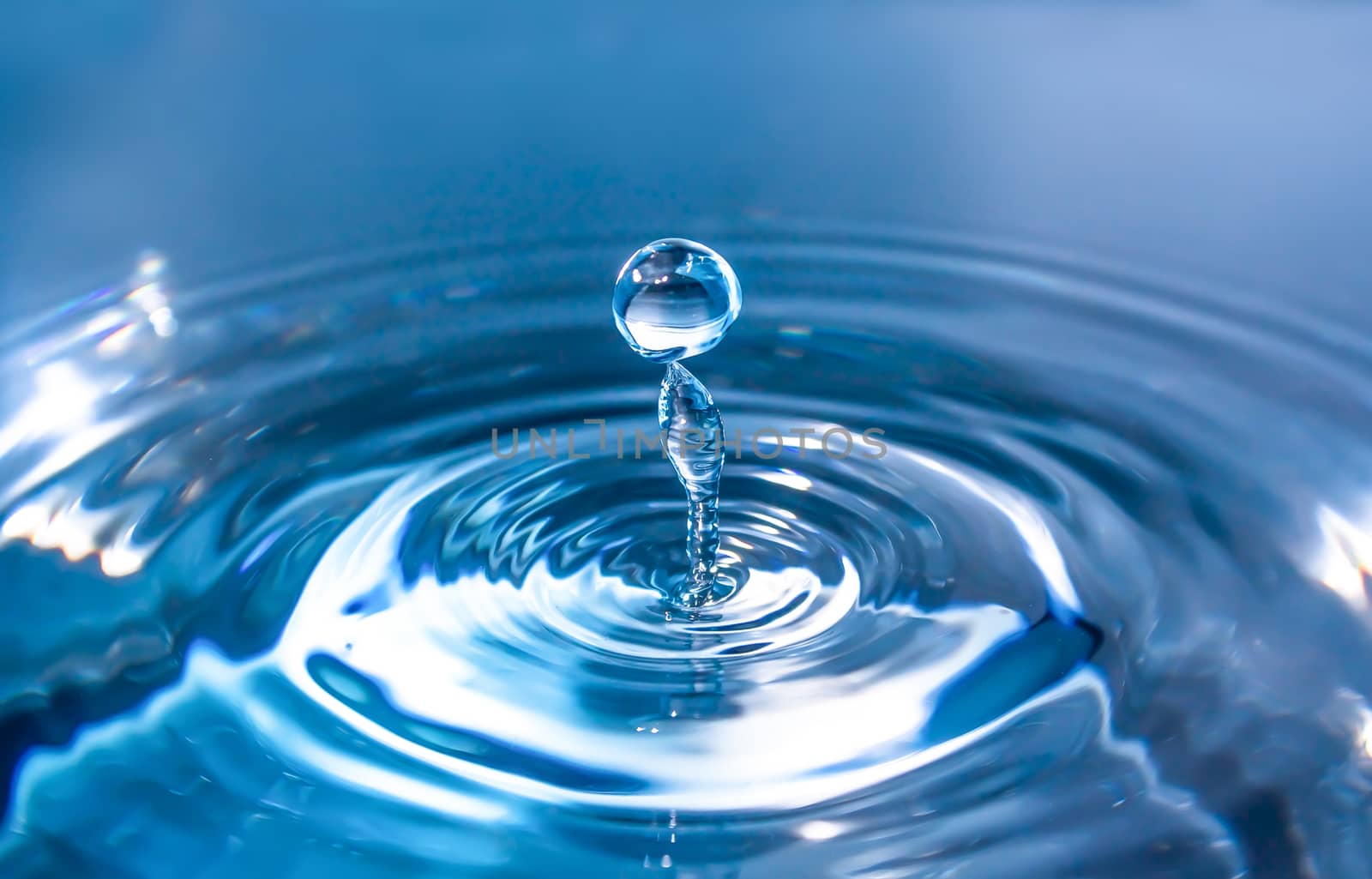 Water splash close-up. Drop of water. Blue water drop. Falling blue water surface with splash and air bubbles