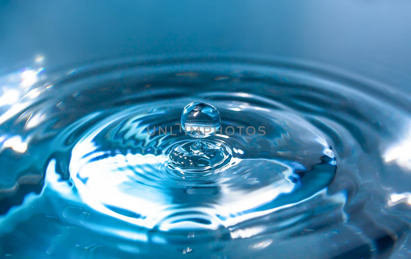 Water splash close-up. Drop of water. Blue water drop. Falling blue water surface with splash and air bubbles