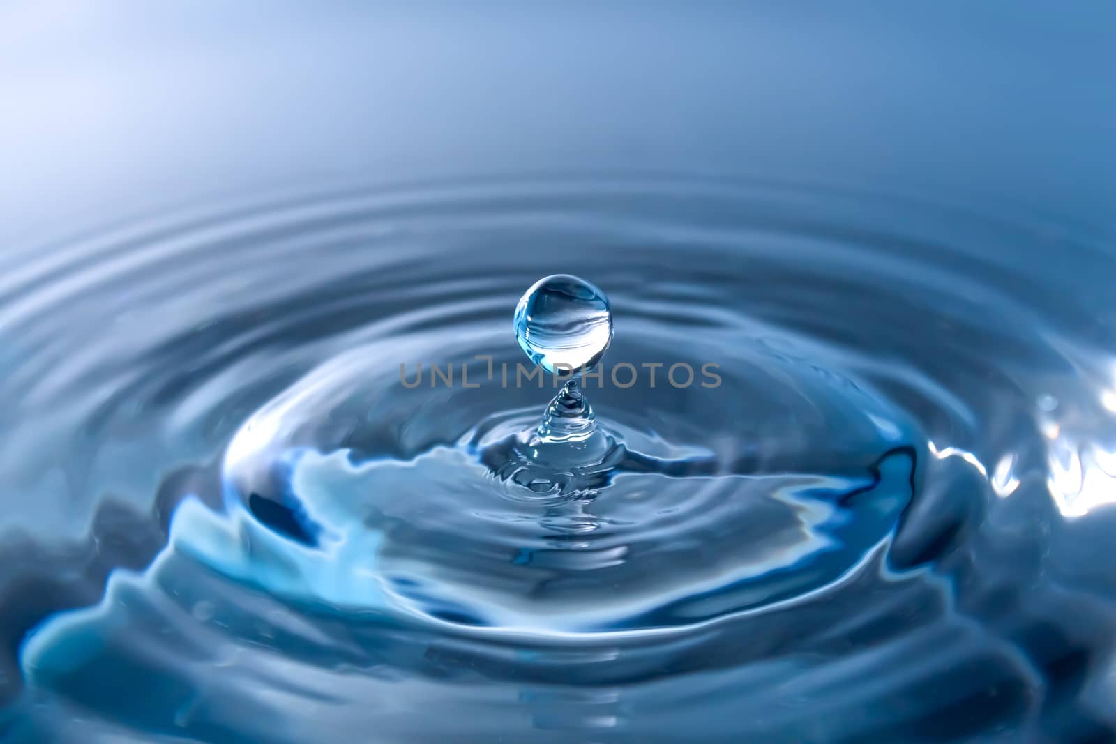 Water splash close-up. Drop of water. Blue water drop. Falling blue water surface with splash and air bubbles