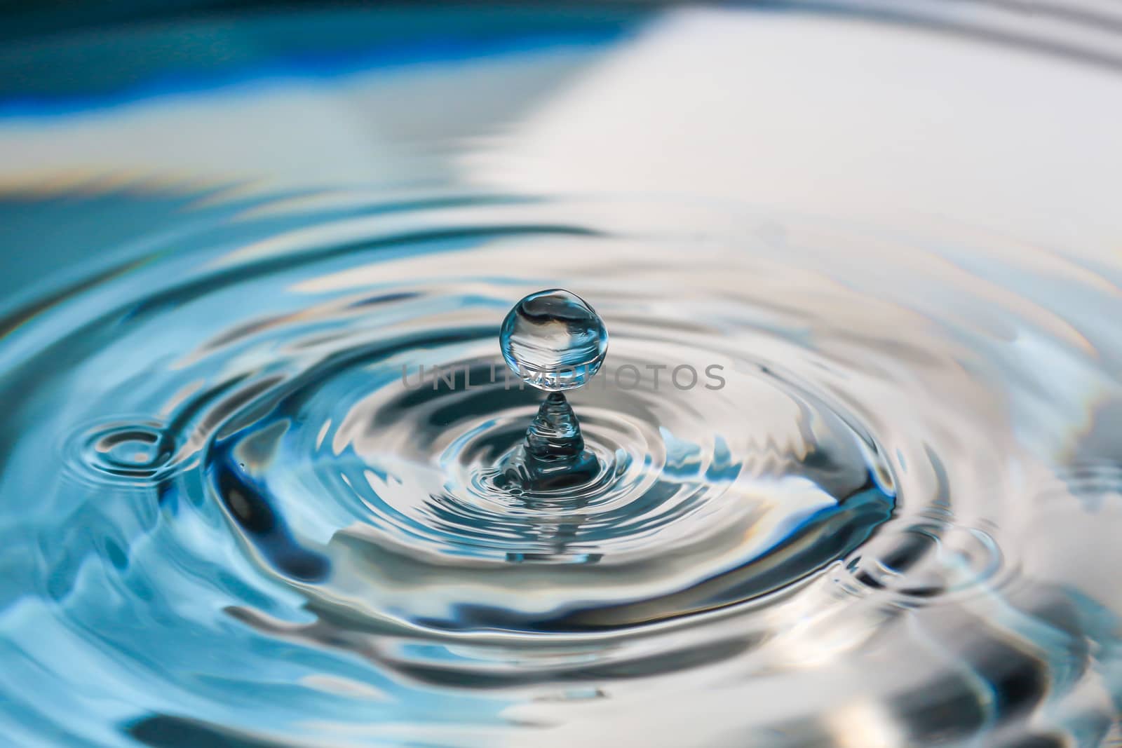 Water splash close-up. Drop of water. Blue water drop. Falling blue water surface with splash and air bubbles