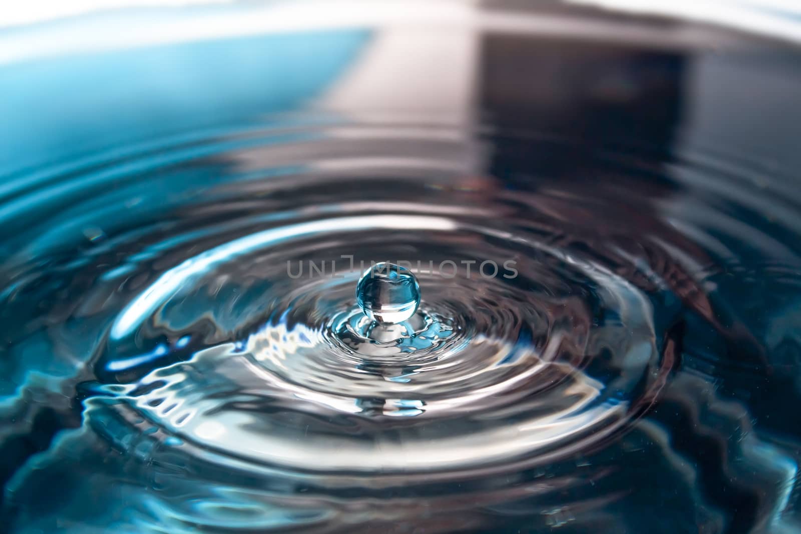 Water splash close-up. Drop of water. Blue water drop. Falling blue water surface with splash and air bubbles