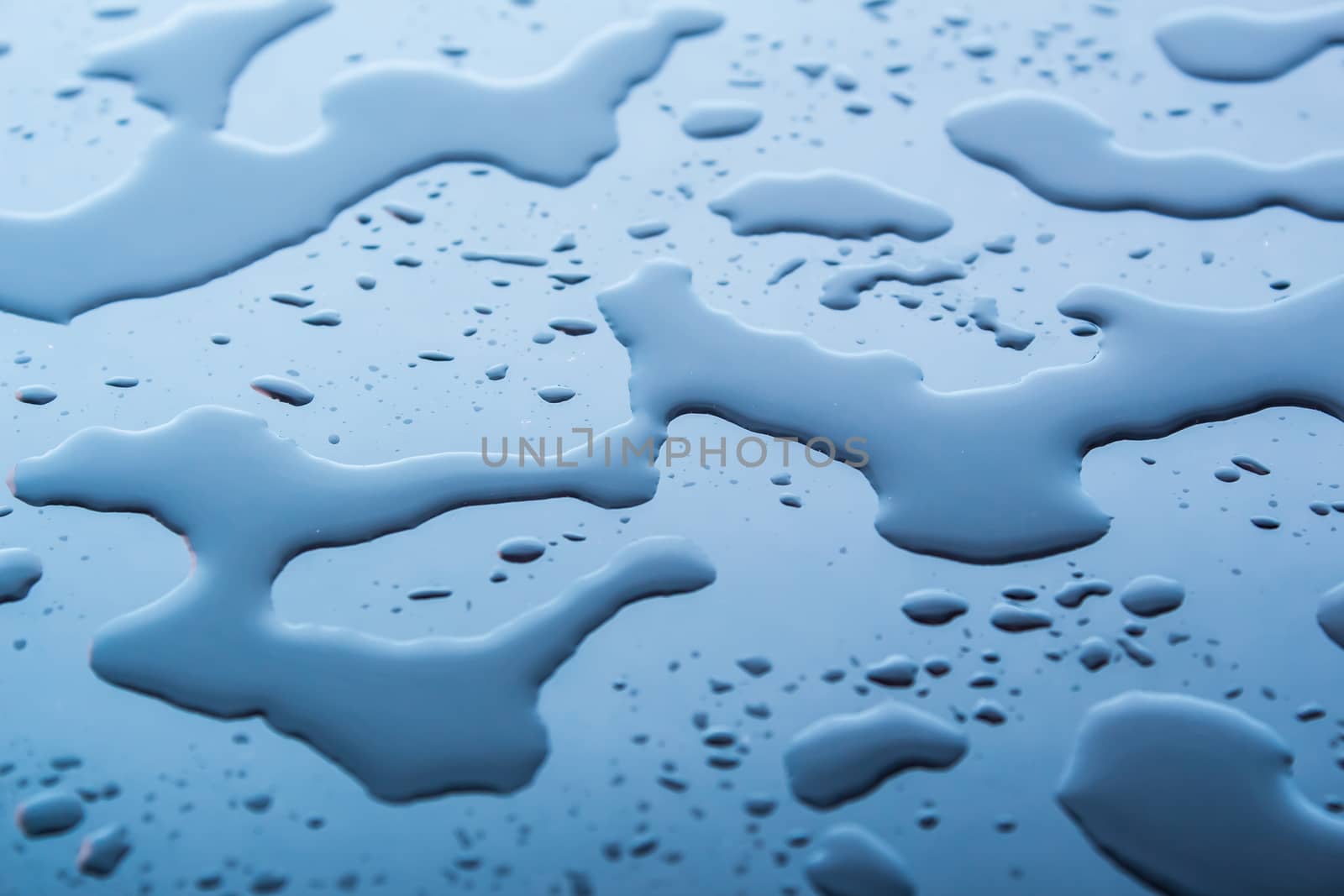 Water on a blue background. Blue drops of water on the glass. Water stains.