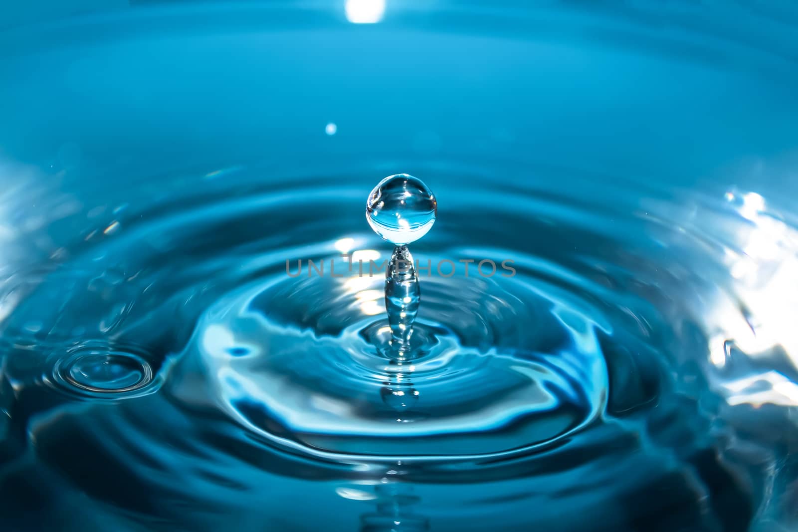 Water splash close-up. Drop of water. Blue water drop. Falling blue water surface with splash and air bubbles